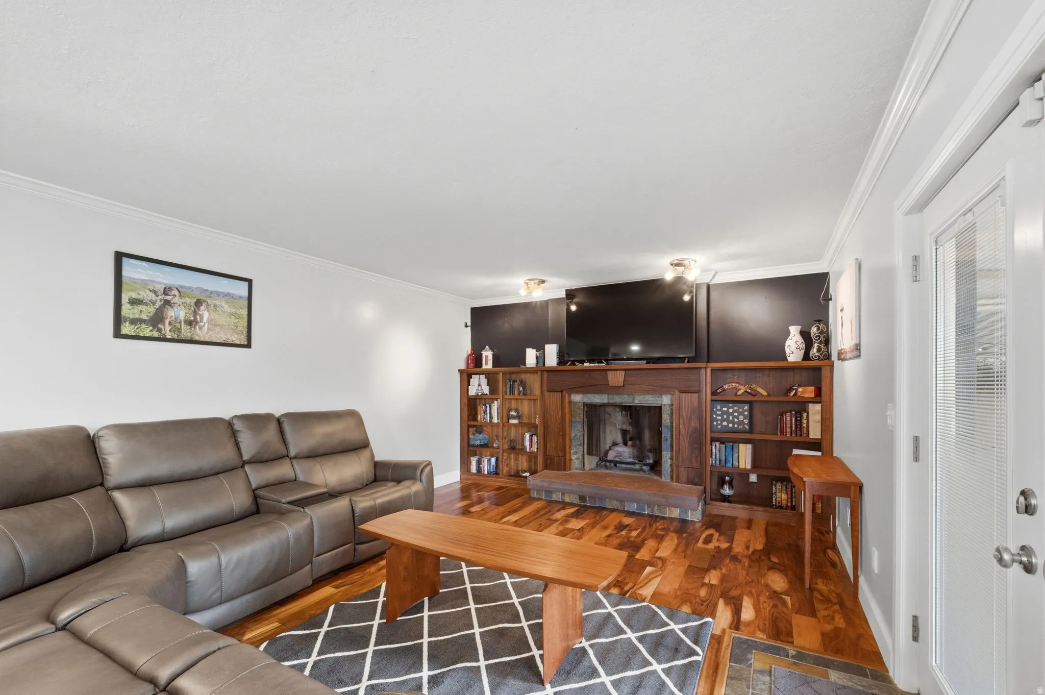 Living room with crown molding, wood finished floors, and a fireplace