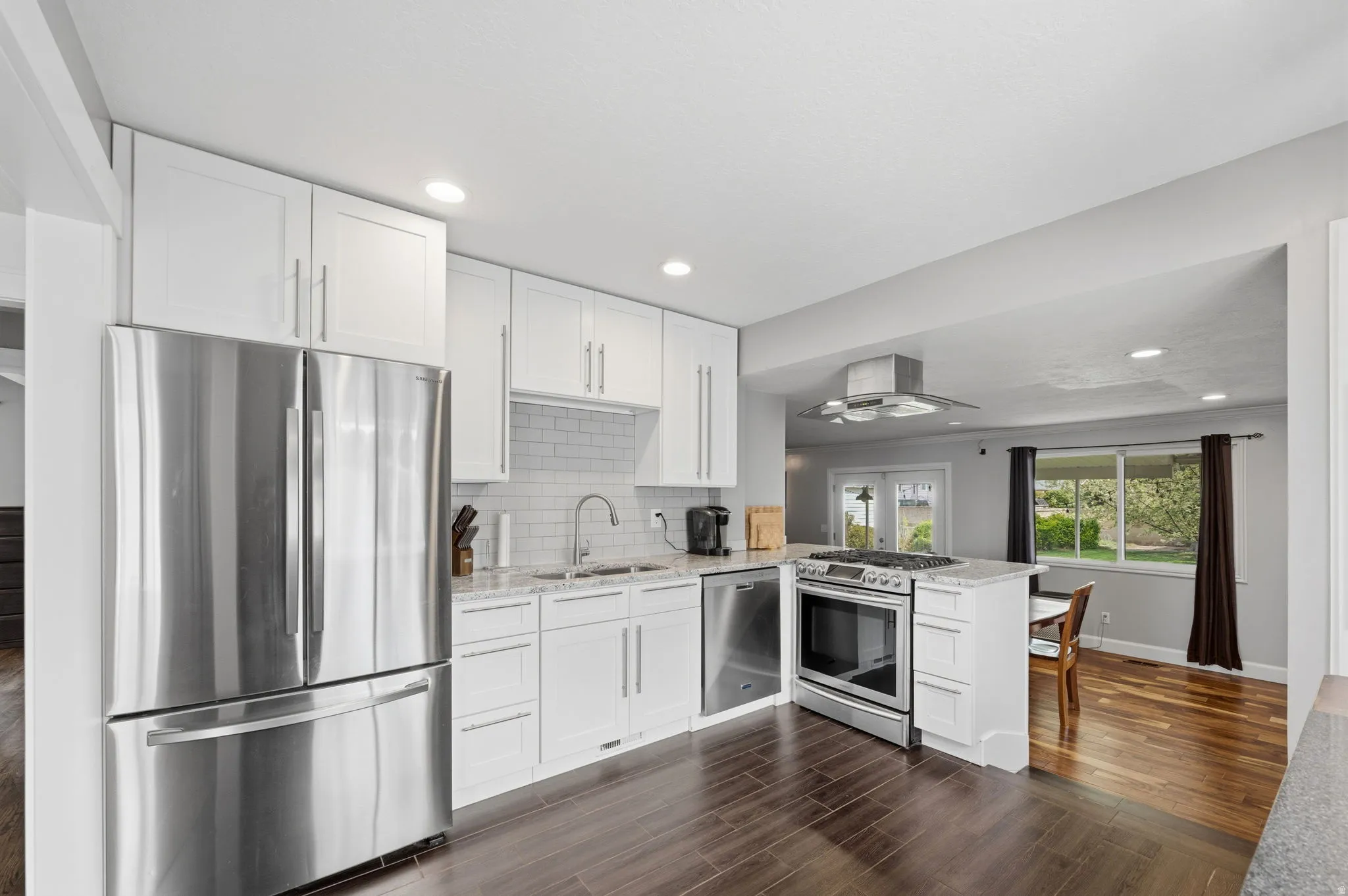 Kitchen featuring stainless steel appliances, light stone countertops, white cabinets, and recessed lighting