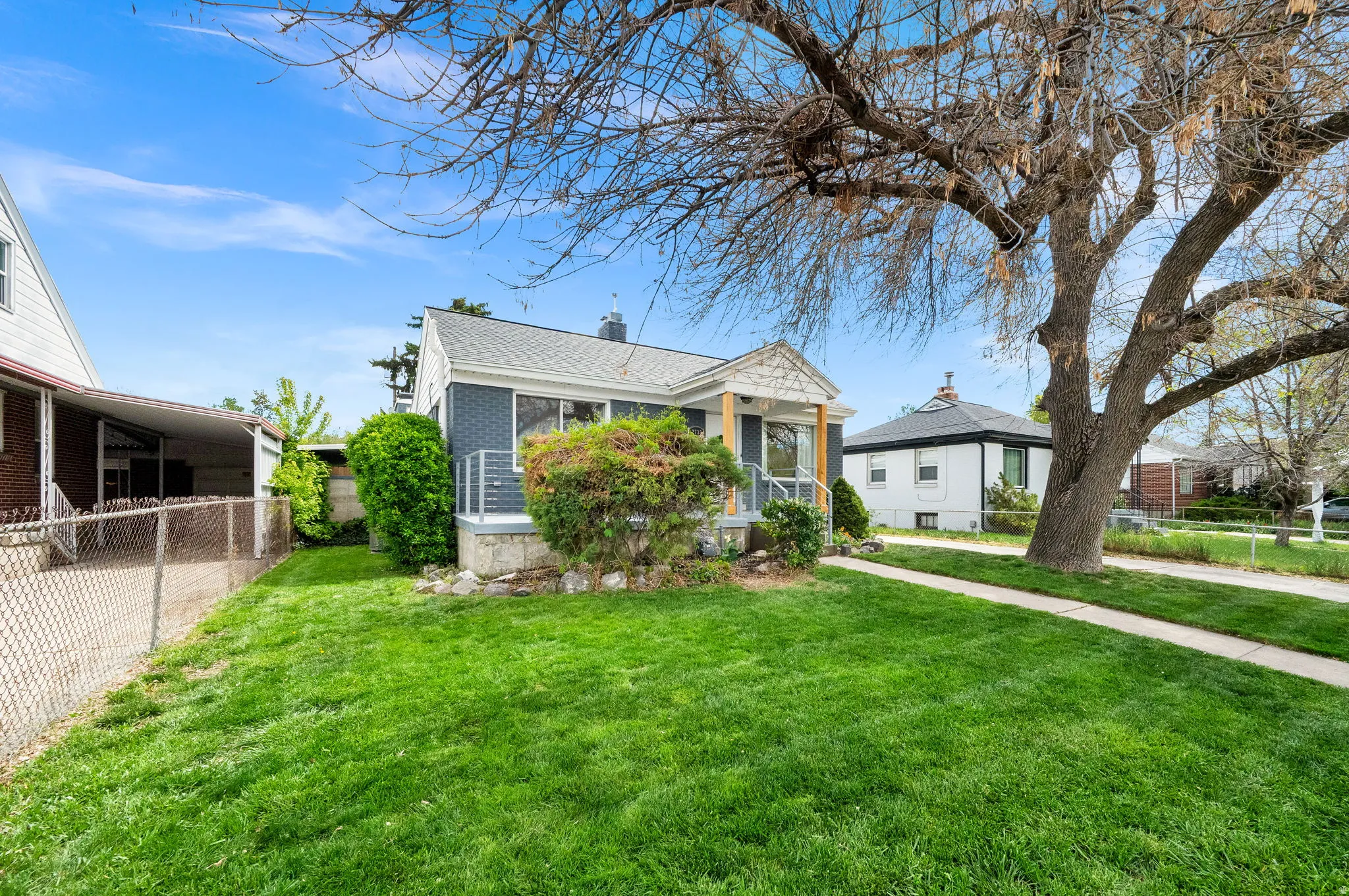 Bungalow-style house featuring a chimney, brick siding, a sunroom, and a shingled roof