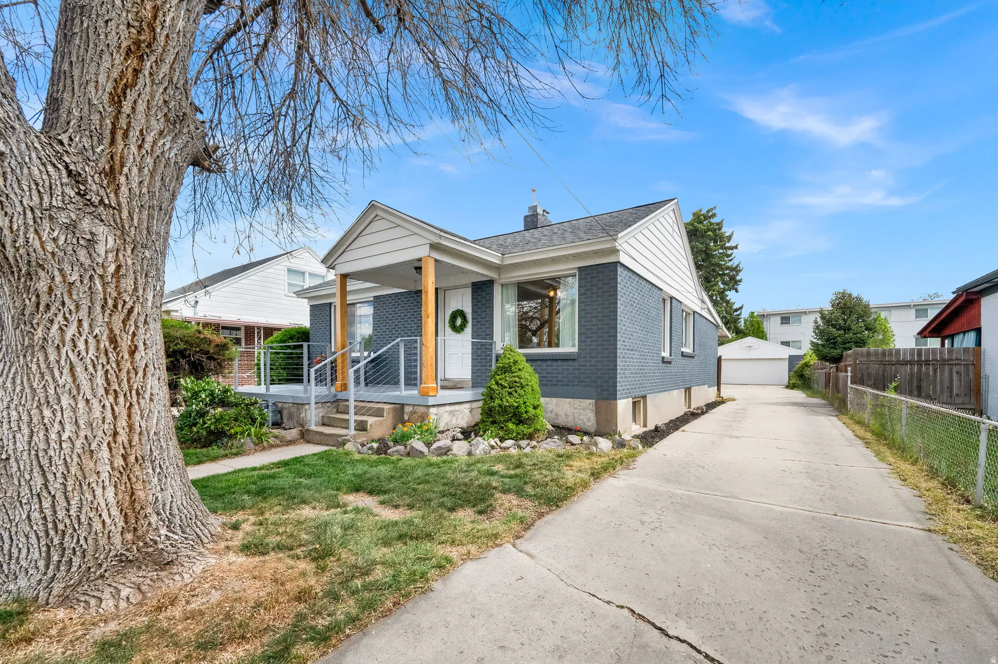 Bungalow-style house with brick siding, an outbuilding, a garage, a chimney, and covered porch