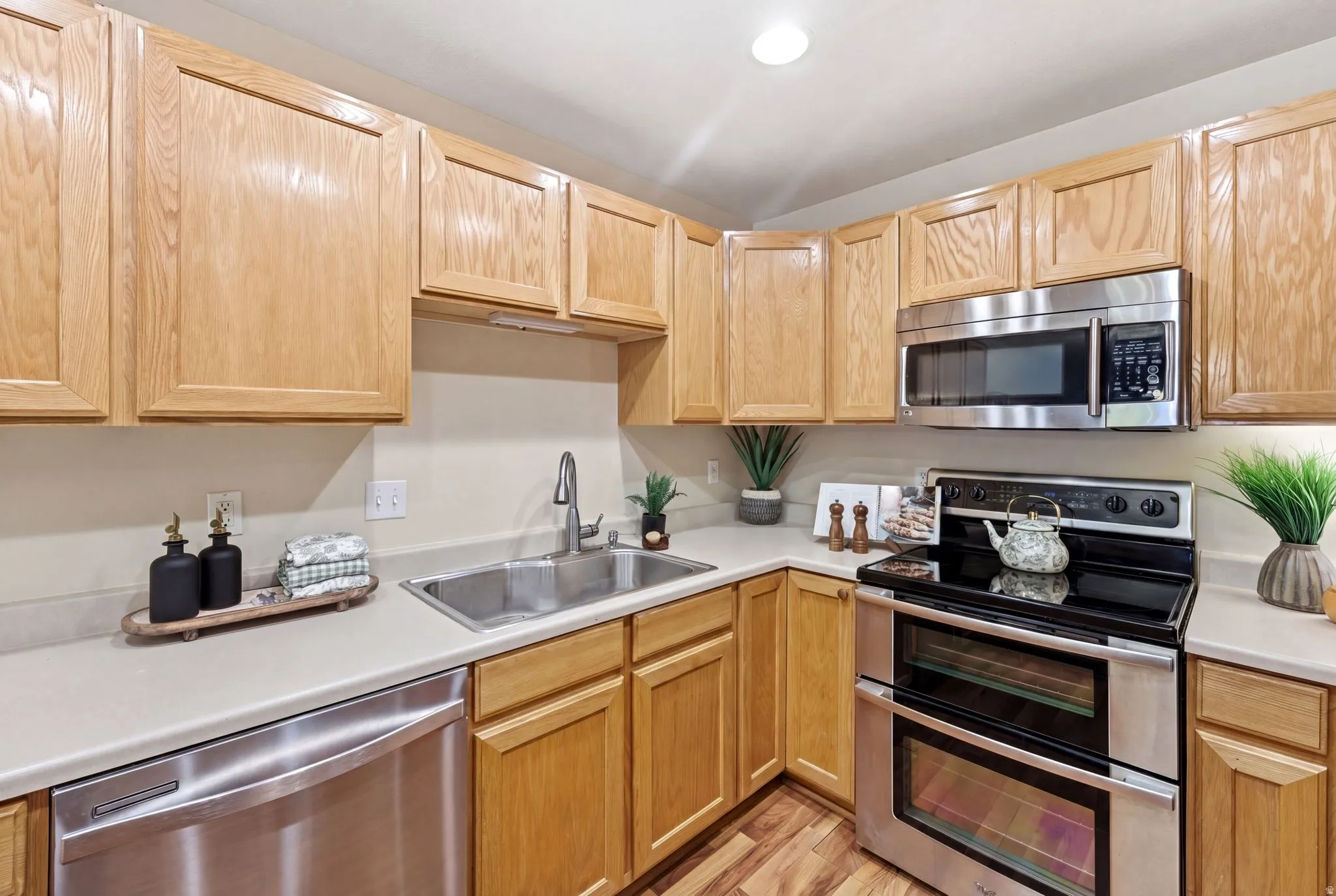 Kitchen with stainless steel appliances, light countertops, light wood finish cabinetry, light wood-type flooring, and recessed lighting