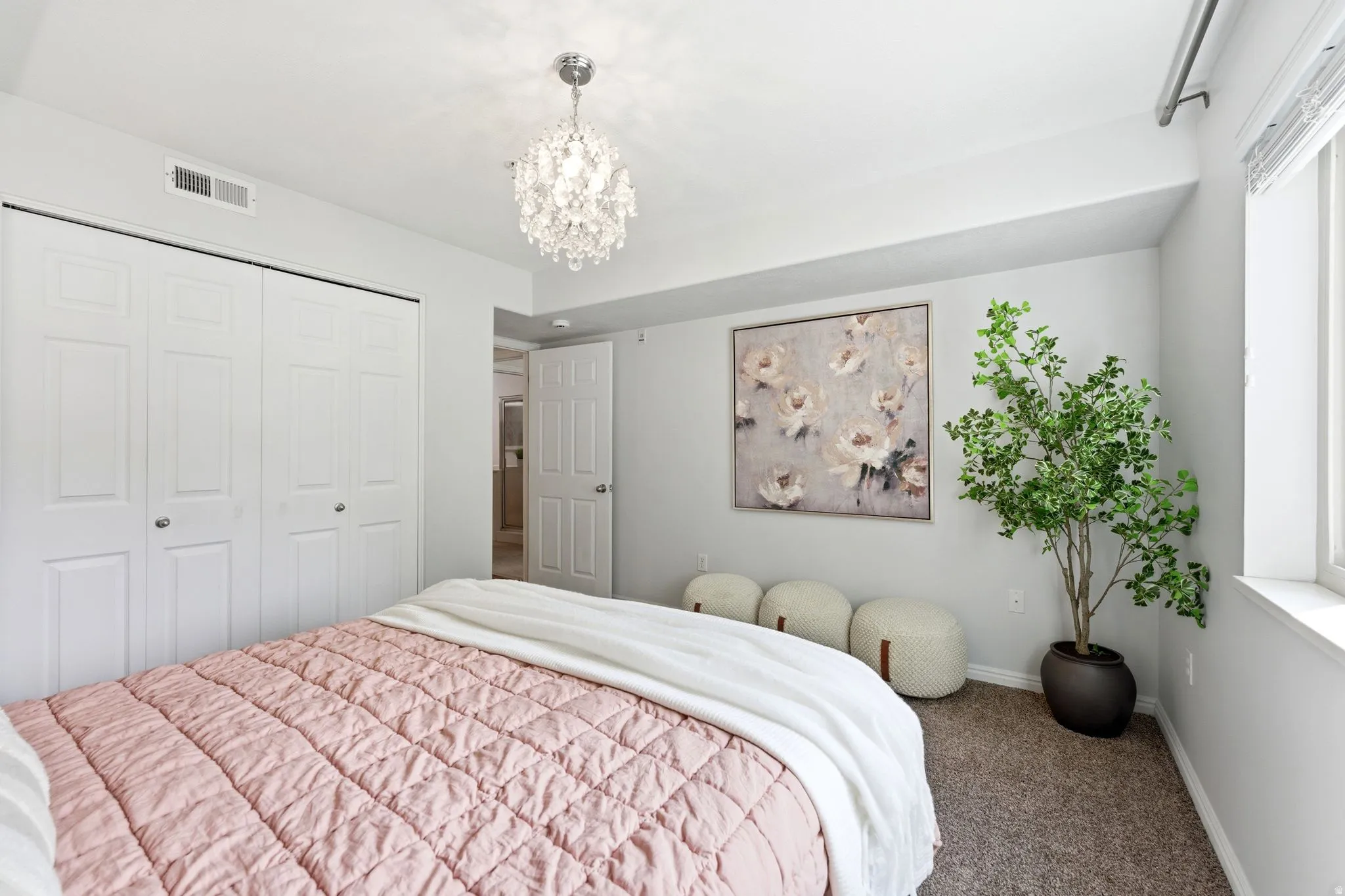 Carpeted bedroom with a chandelier and a closet