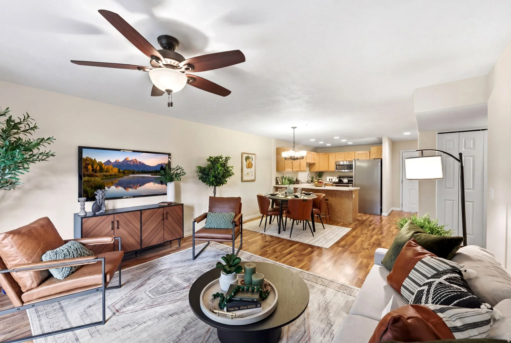 Living area featuring light wood finished floors, a ceiling fan, and a chandelier