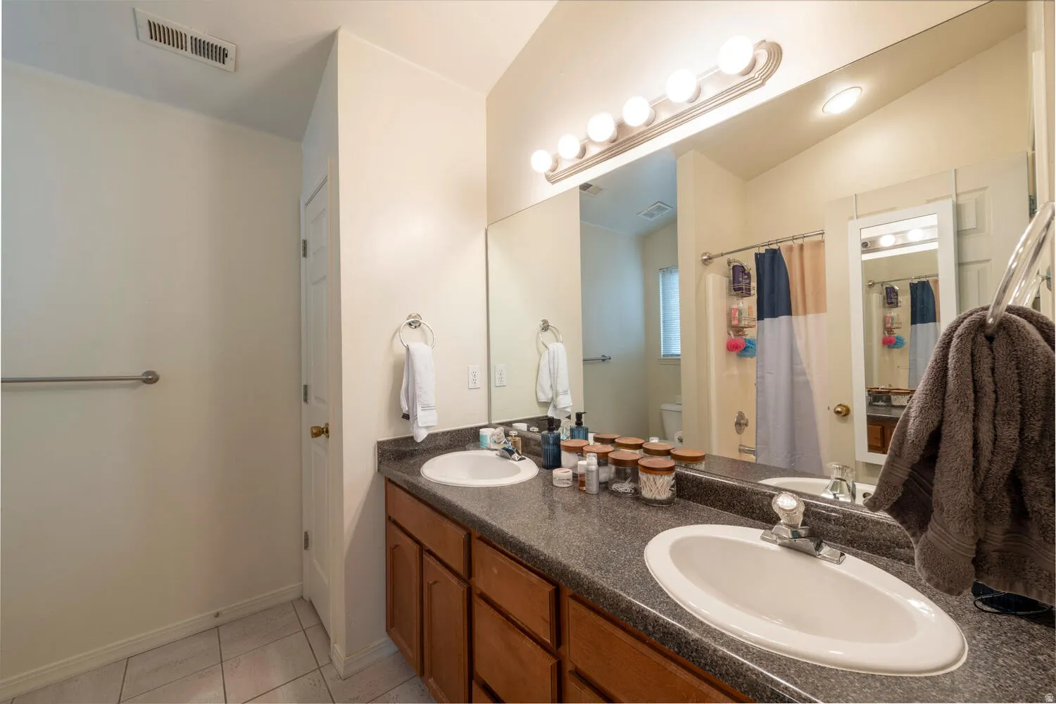 Bathroom featuring double vanity, shower/tub and small storage closet
