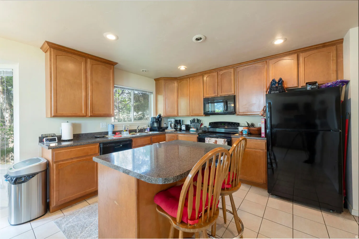 Kitchen with black appliances, dark countertops, a breakfast bar area