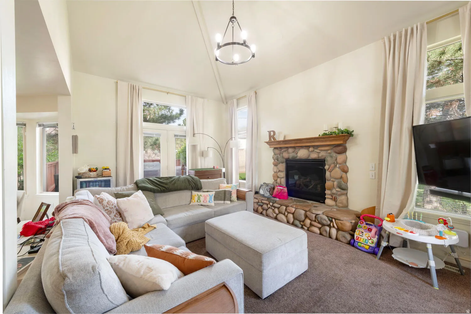 Living room featuring a stone fireplace and vaulted ceiling