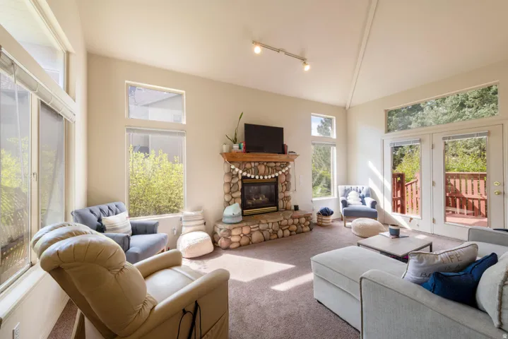 Living room featuring a stone fireplace with vaulted ceiling