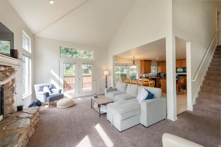 Living area with a stone fireplace, recessed lighting, and lofted ceiling looking out onto the deck