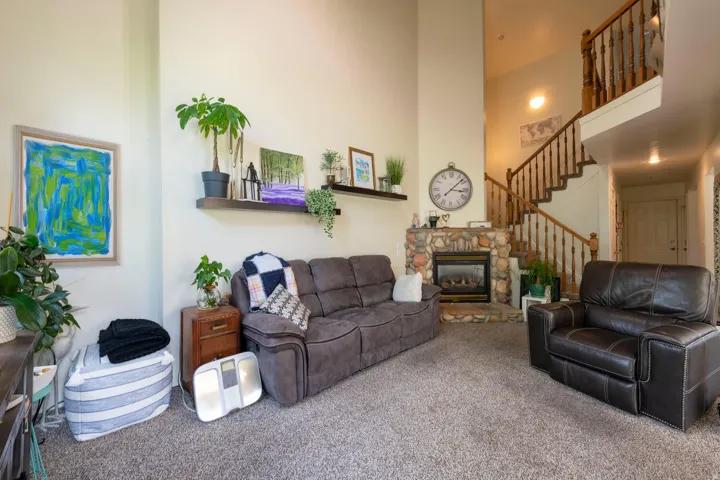 Living area featuring a high ceiling, carpet floors, and a stone fireplace