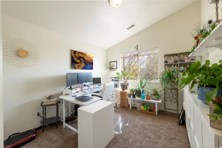 Carpeted home office with lofted ceiling