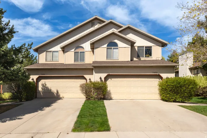 View of front of duplex featuring a garages, driveways, and stucco siding