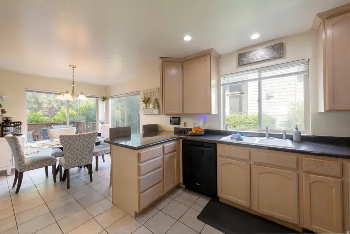 Kitchen featuring light wood finish cabinetry, a peninsula, black appliances overlooking the dining area