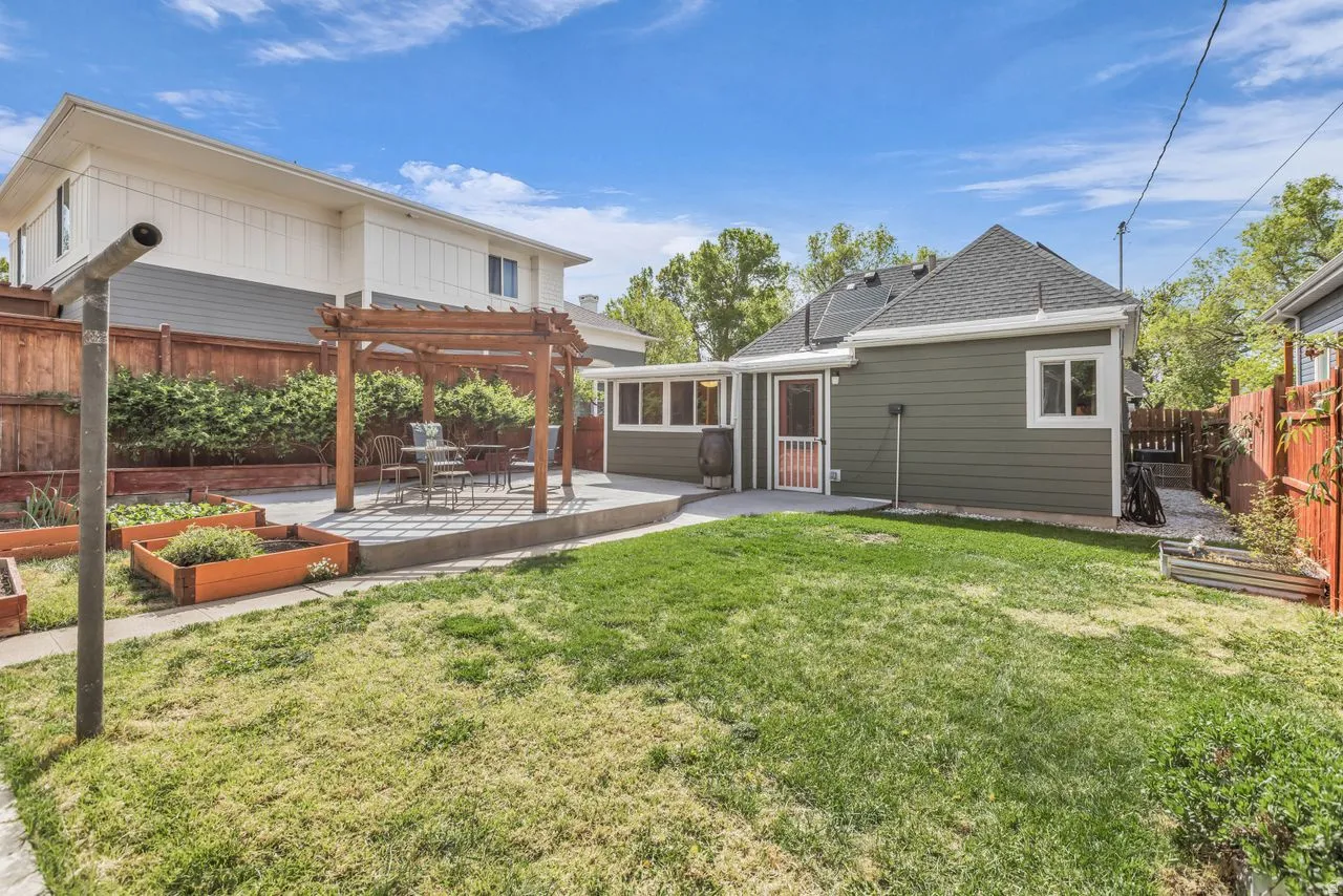 Rear view of house featuring a vegetable garden, a patio area, a fenced backyard, and a pergola