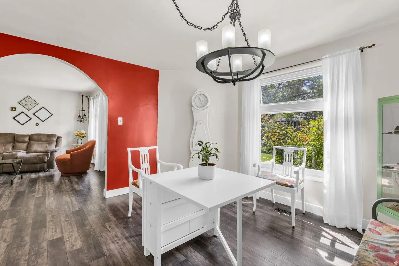 Dining room with arched walkways, suspended lighting, and dark wood-type flooring