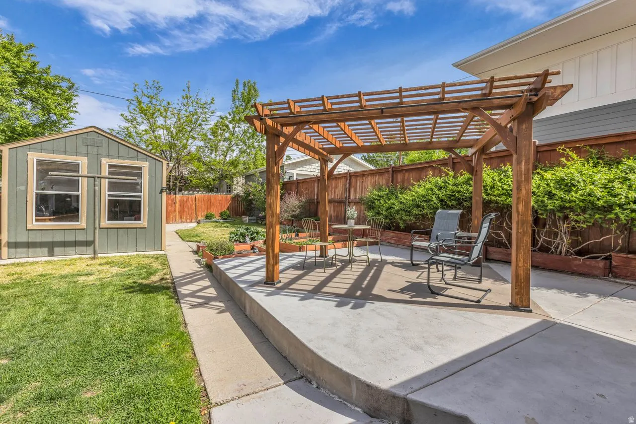 Fenced backyard with a pergola, a patio area, and an outdoor structure