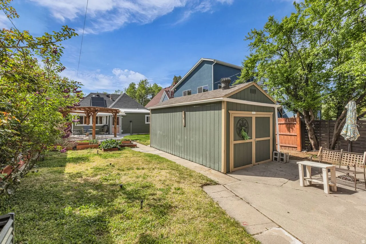 Back of house featuring an outbuilding, a fenced backyard, a pergola, and a patio area