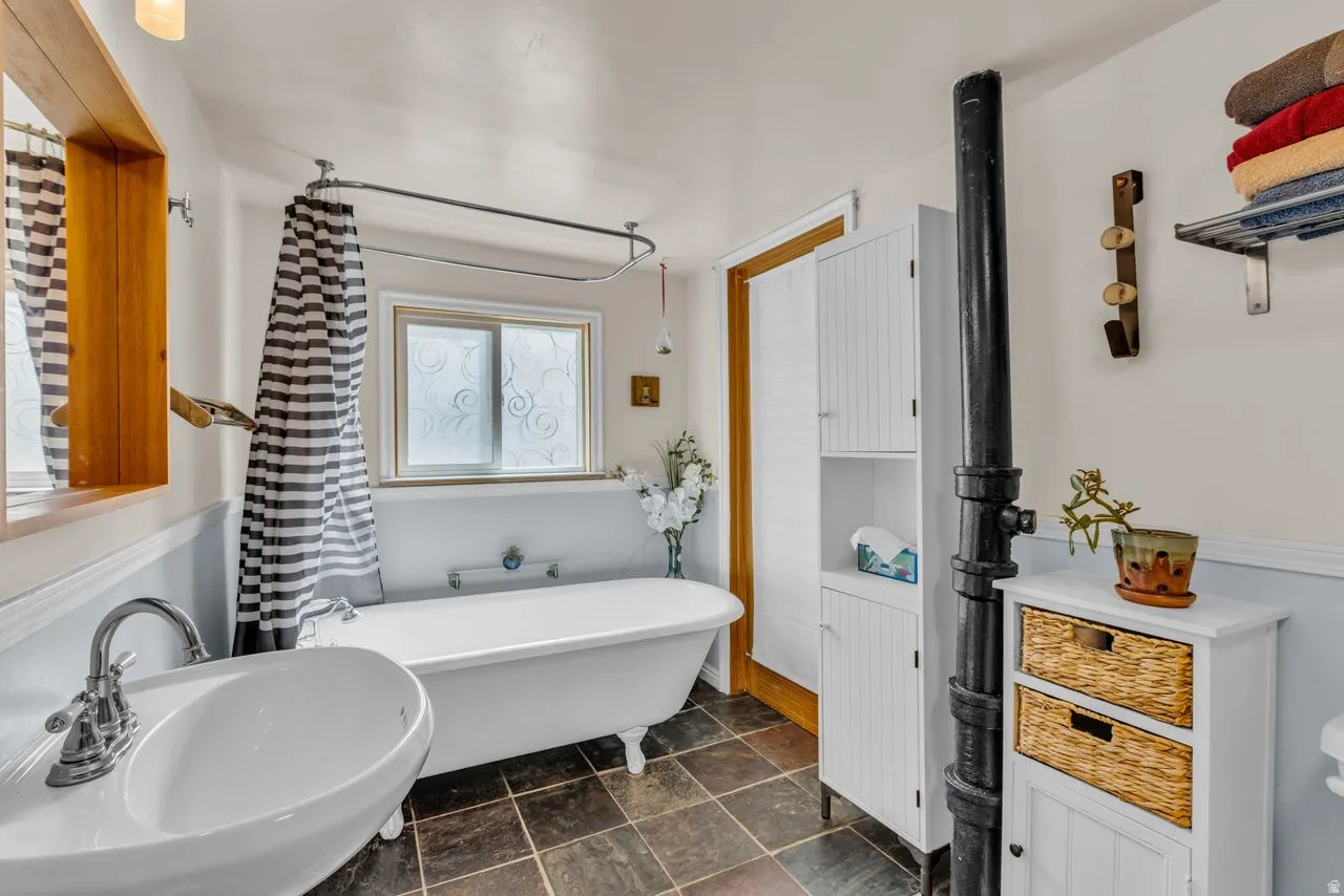 Full bath featuring a freestanding tub and dark stone finish floors