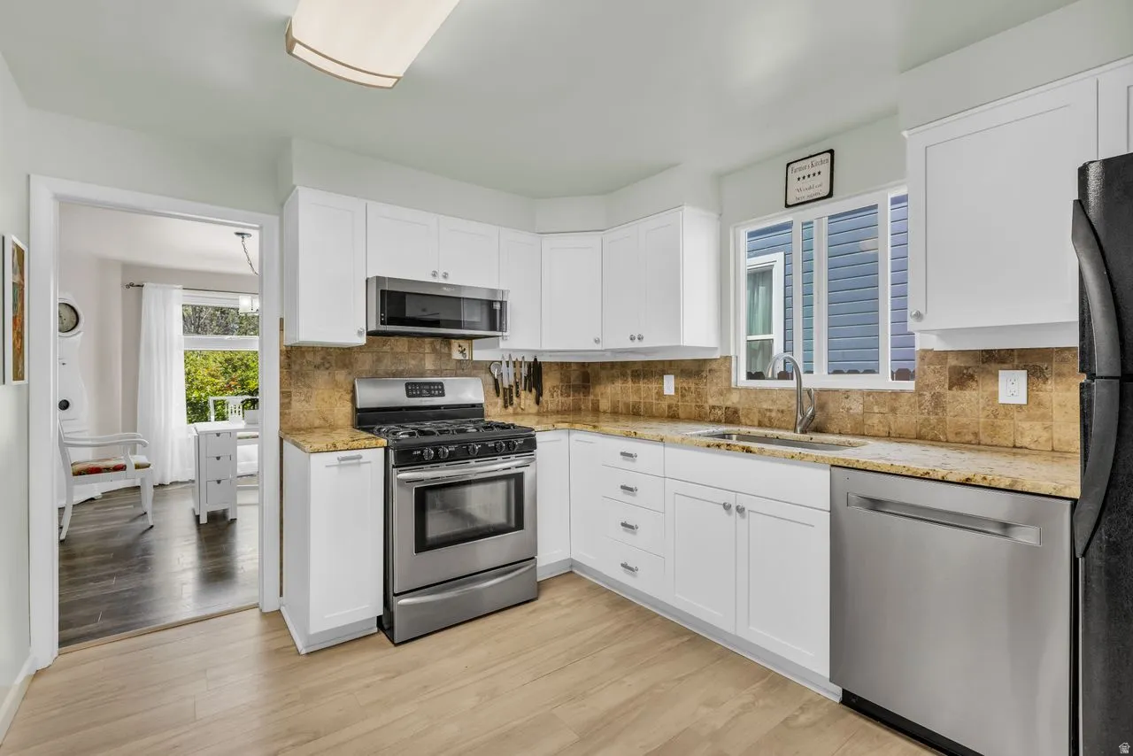 Kitchen featuring stainless steel appliances, light stone counters, and white cabinets