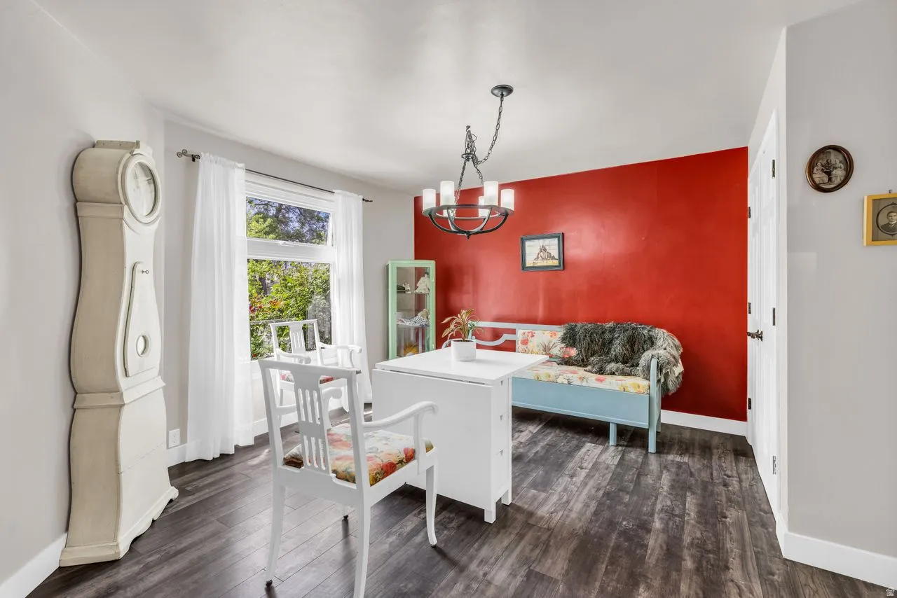 Dining area featuring a chandelier, dark wood-type flooring, and an accent wall