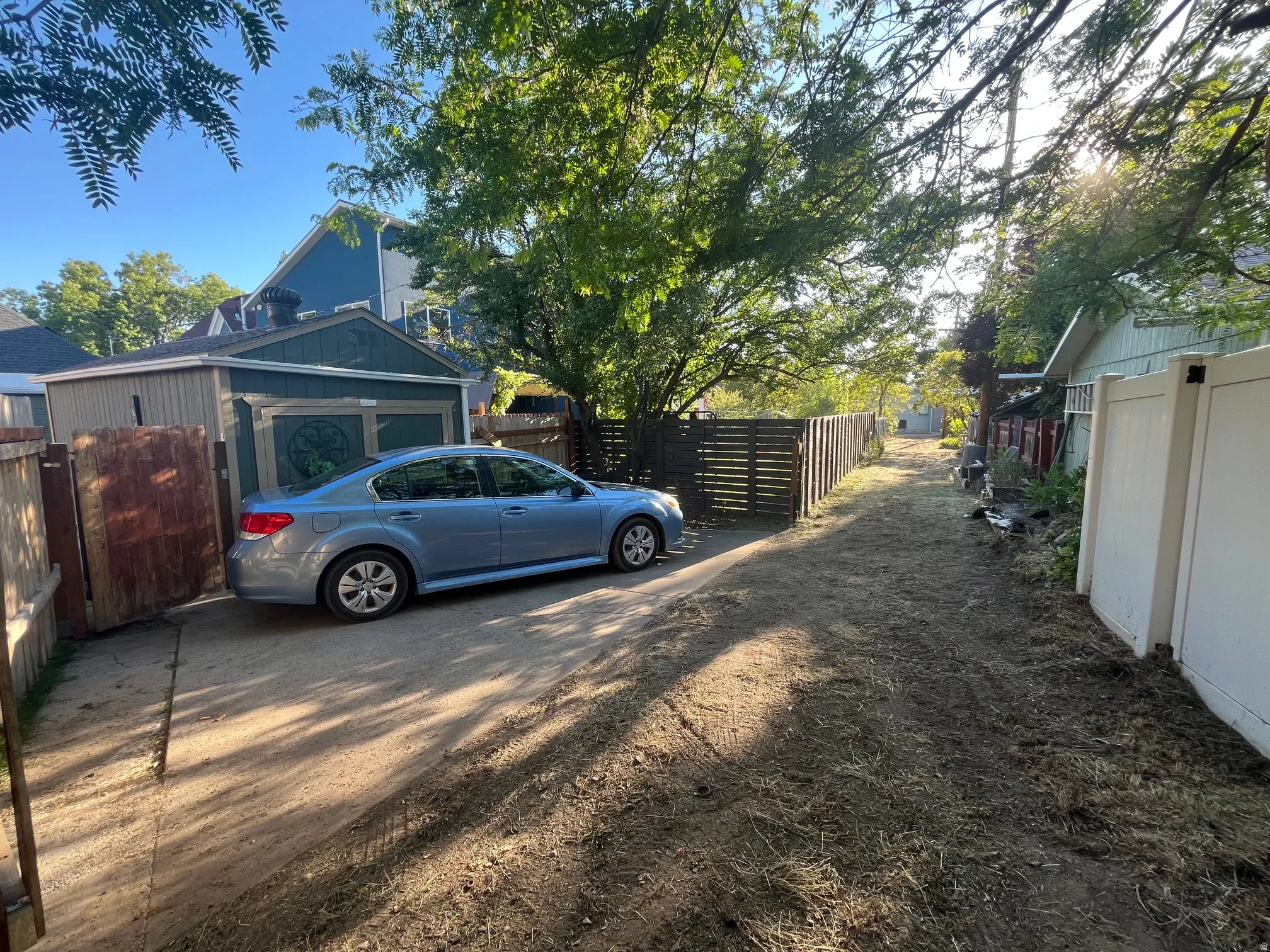 Detached garage with a paneled door and light blue trim, featuring a concrete driveway