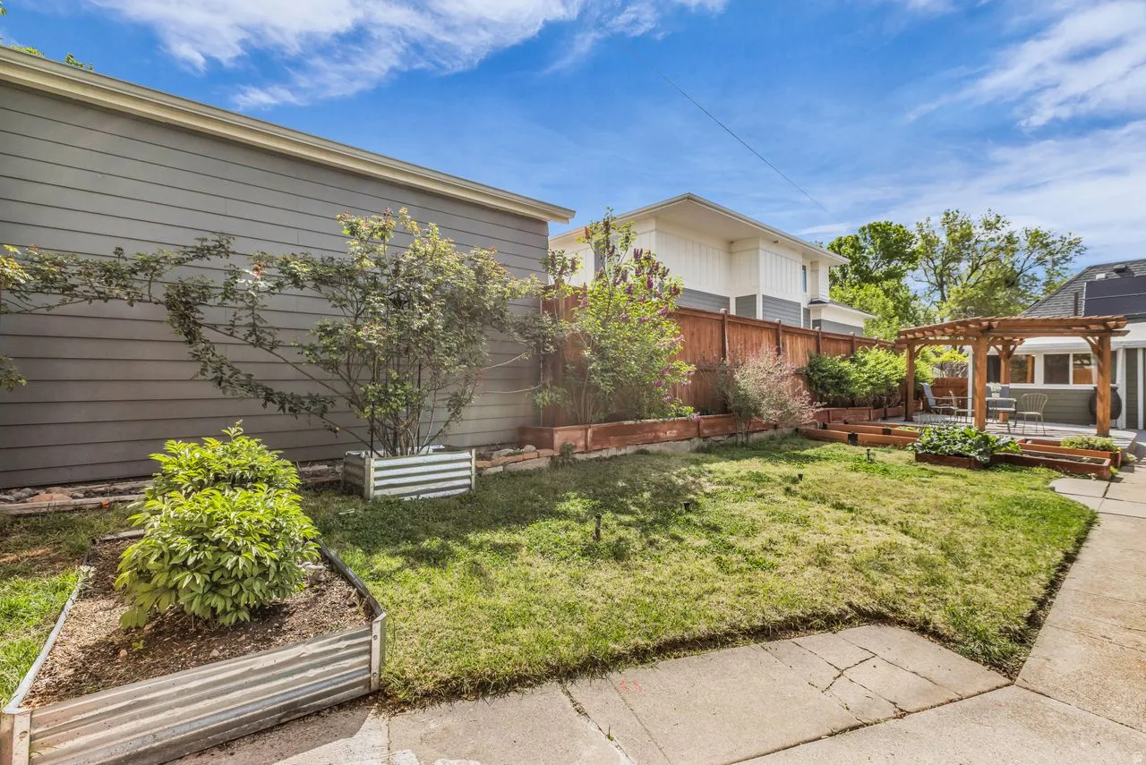 Fenced backyard with a garden, a pergola, and a deck