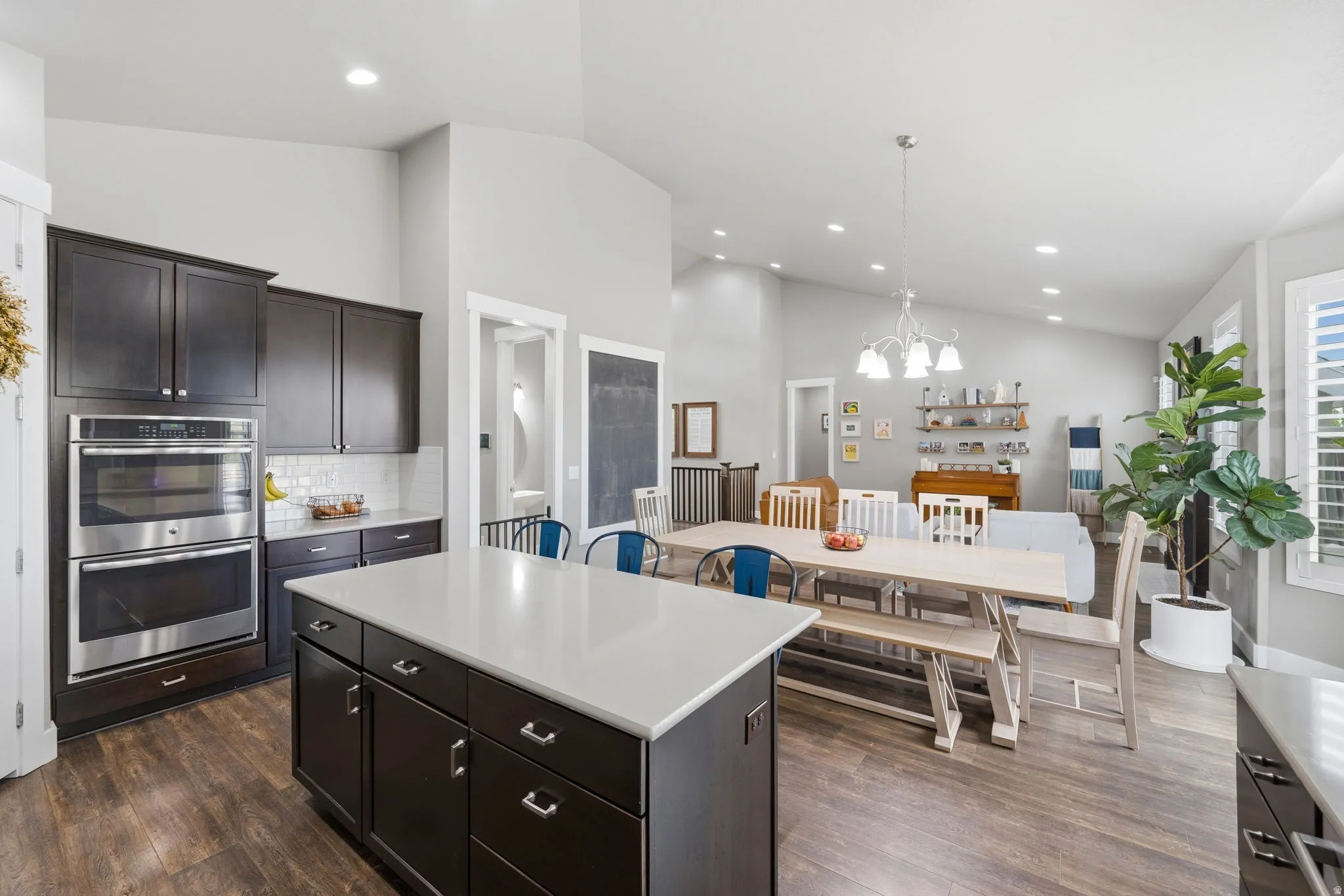 Kitchen featuring double oven, dark wood finish cabinetry, a center island, tasteful backsplash, and dark wood-type flooring
