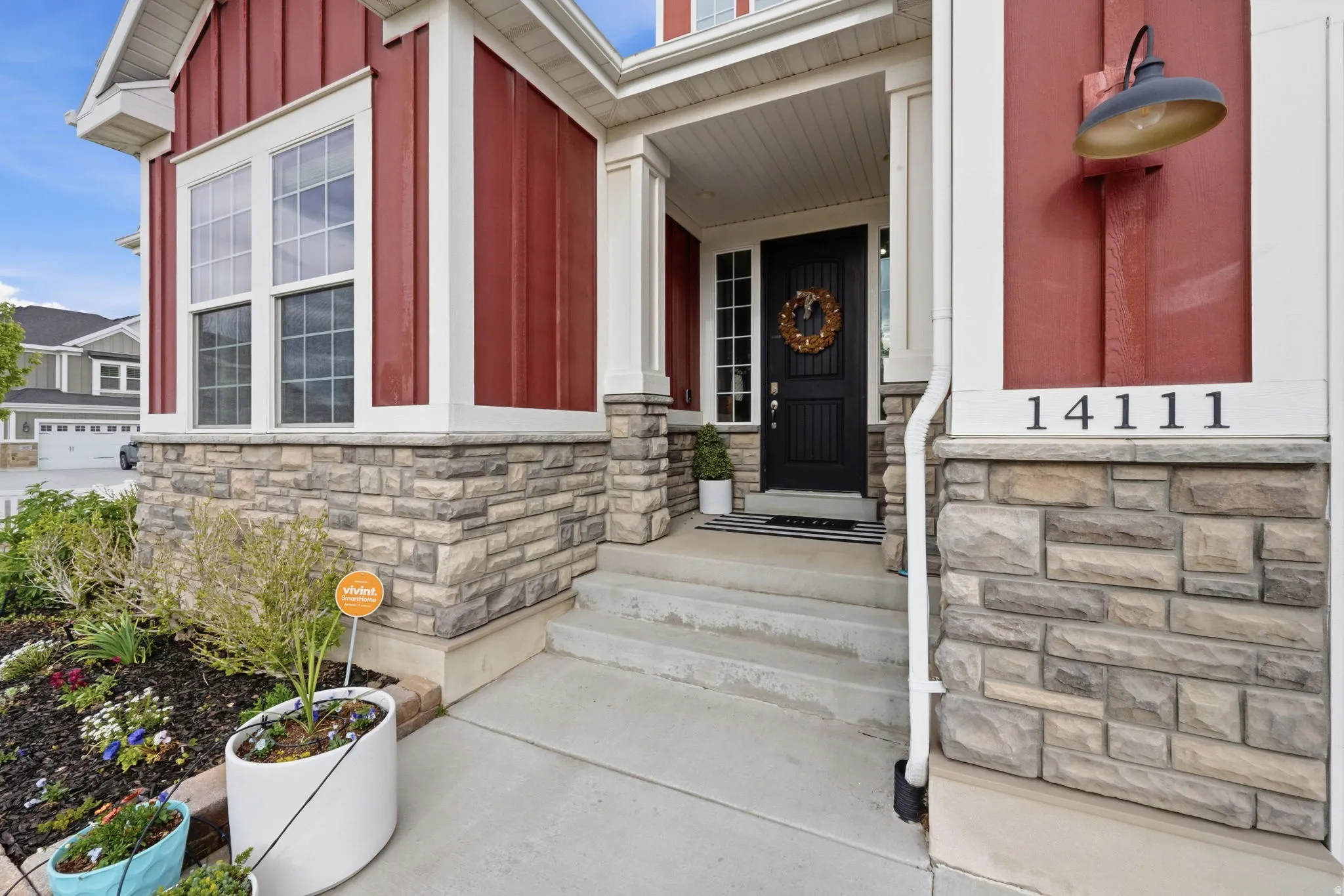 Property entrance with board and batten siding, stone siding, and a porch