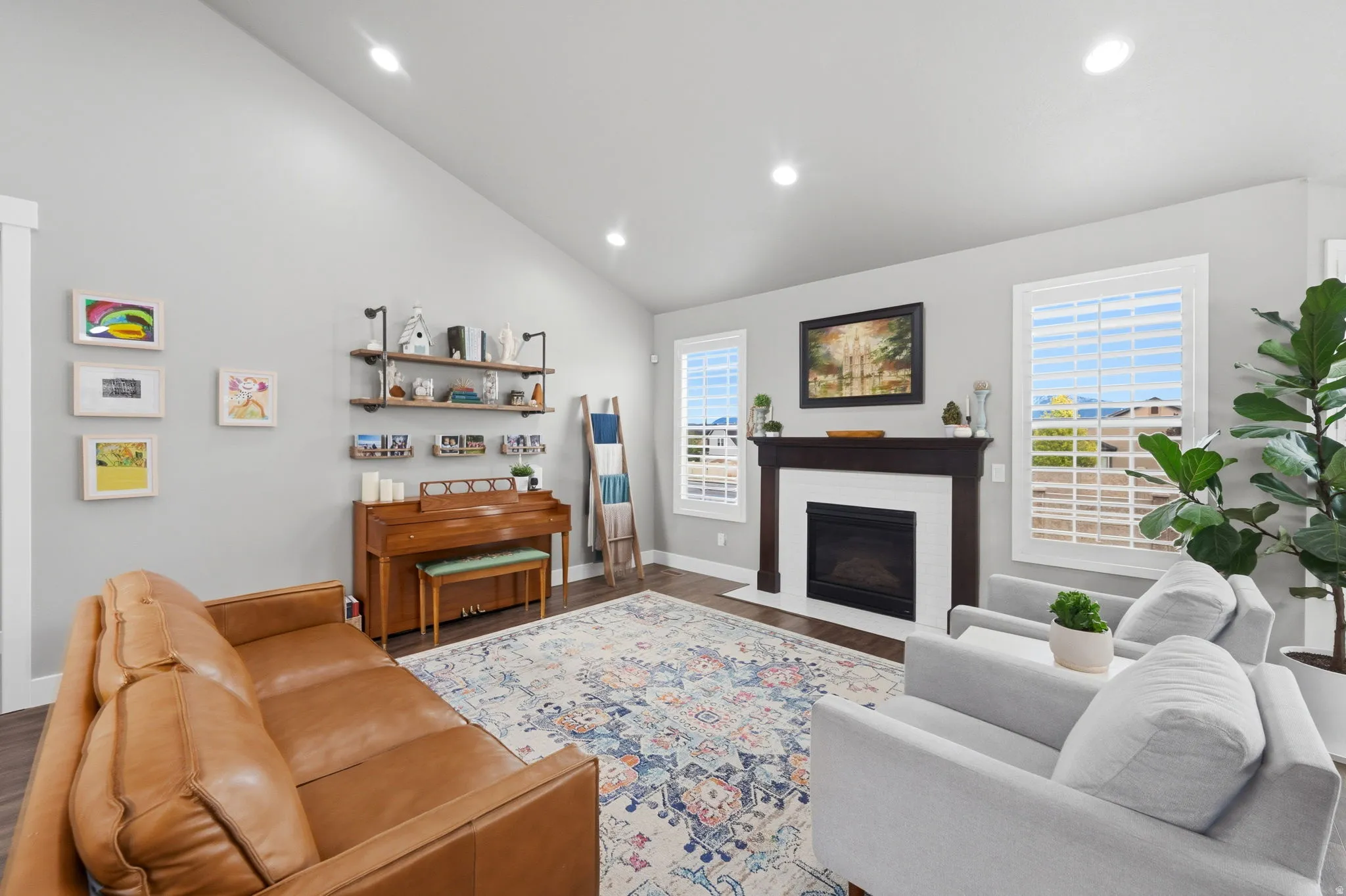 Living room featuring vaulted ceiling, a fireplace with flush hearth, wood finished floors, and recessed lighting