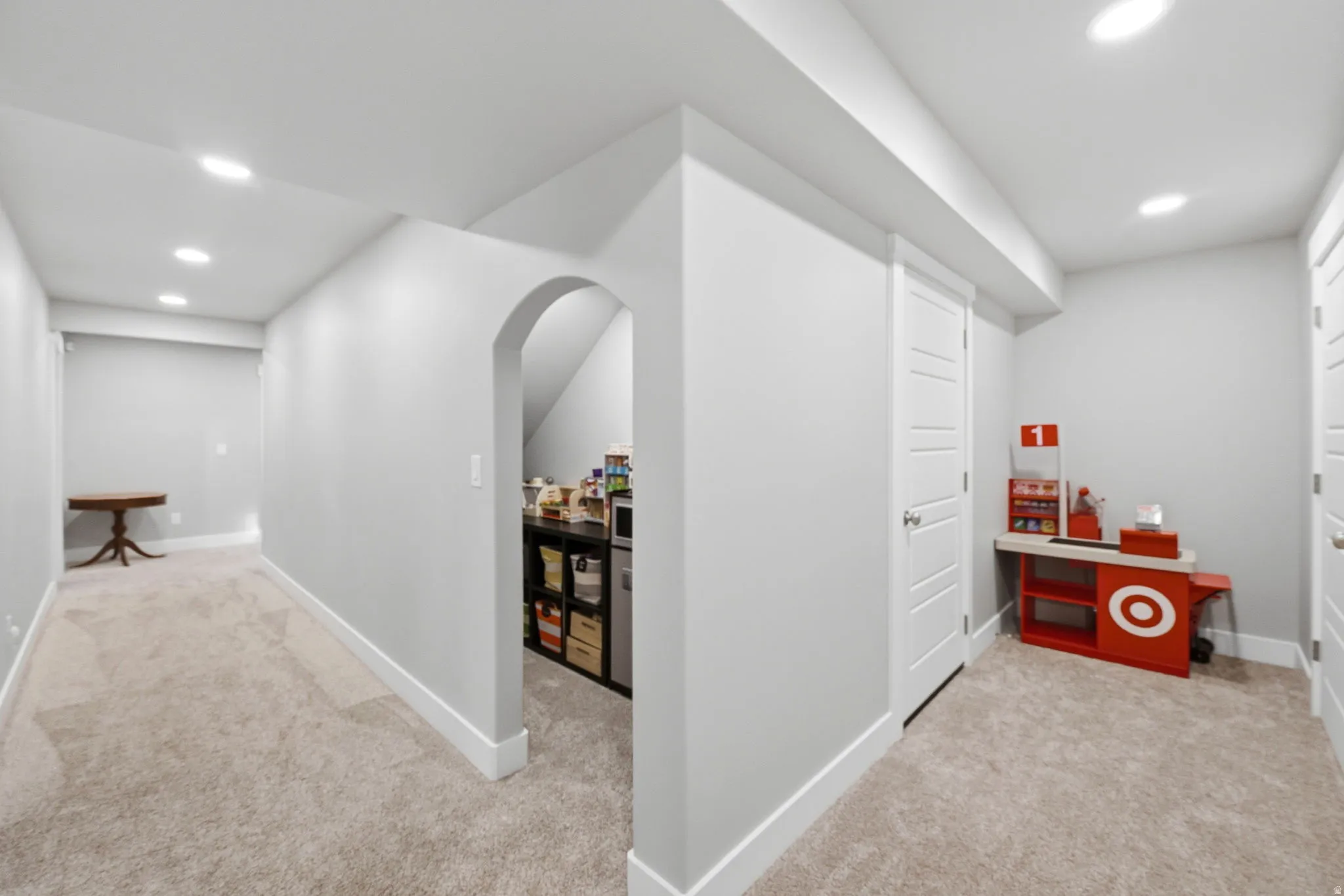 Hallway with light carpet, recessed lighting, and arched walkways