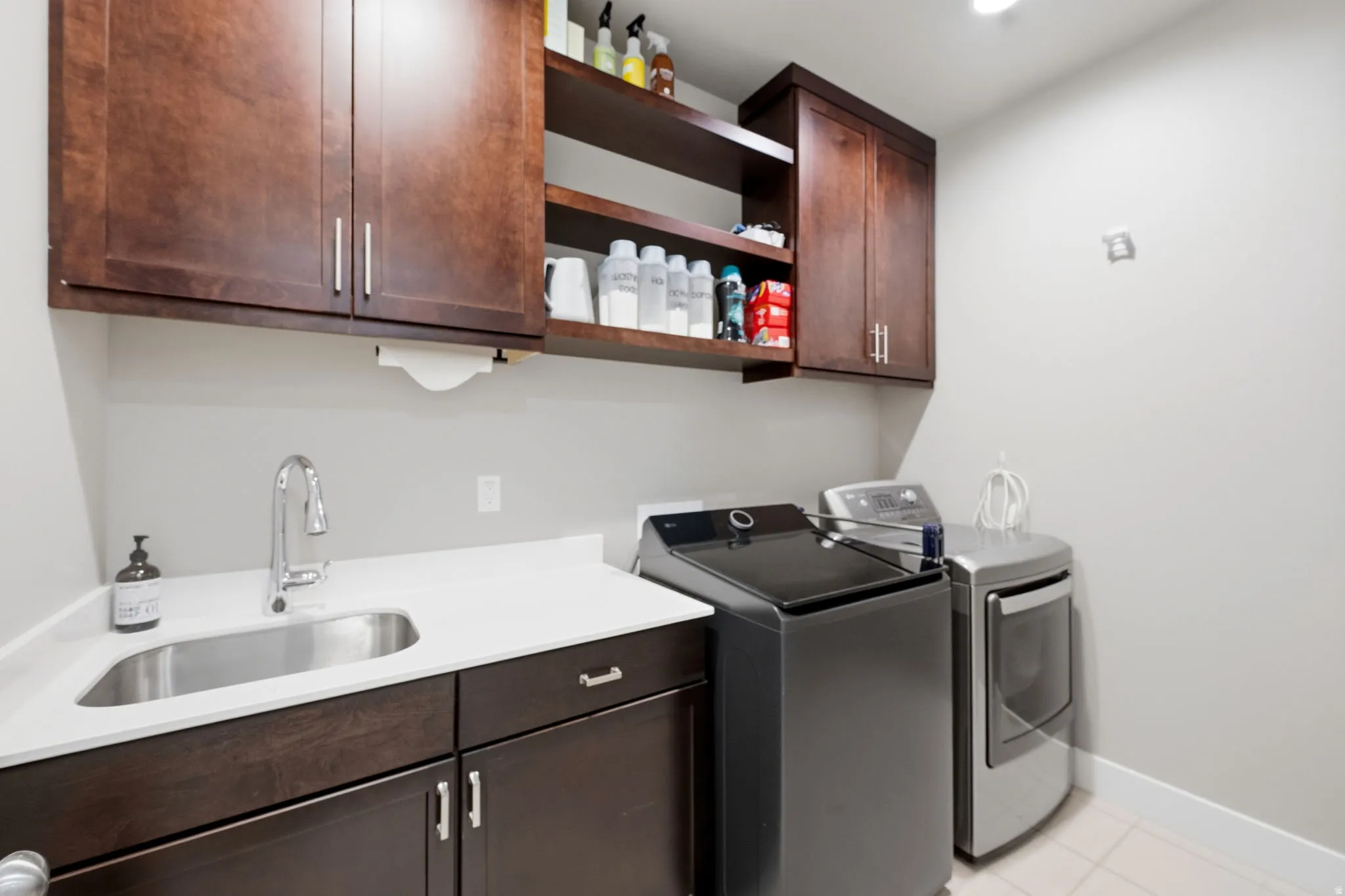 Laundry room featuring cabinet space, washer and clothes dryer, light tile patterned floors, and sink