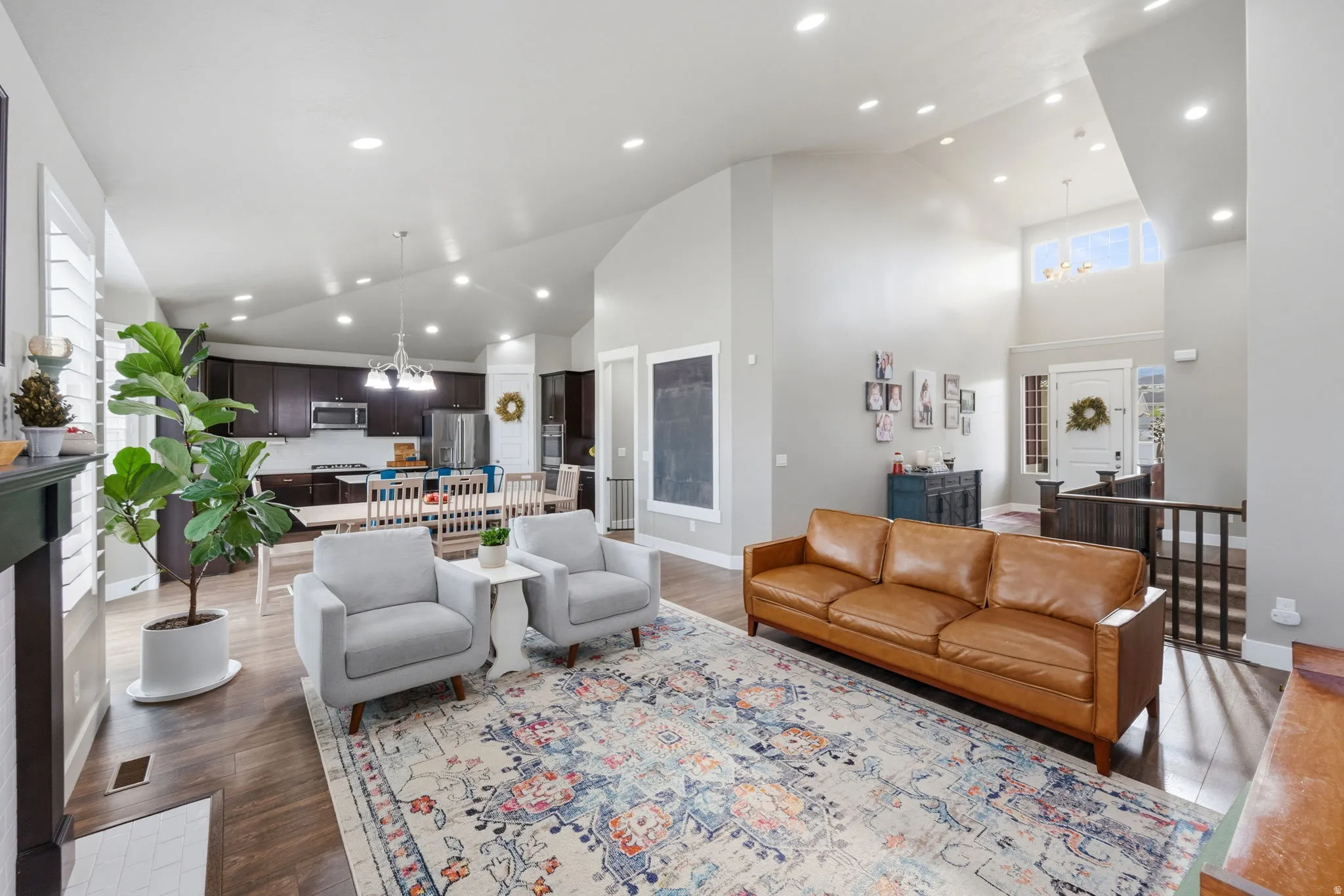 Living area with hanging lights, vaulted ceiling, light wood-style flooring, and a fireplace