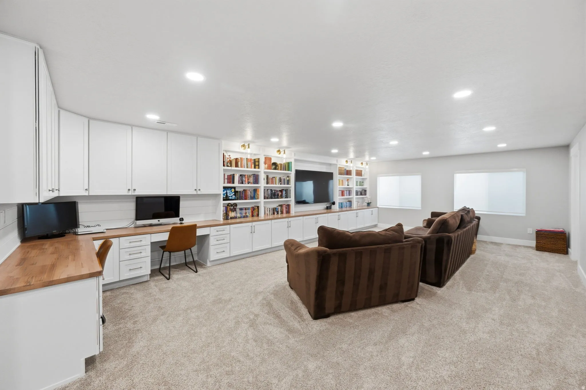 Living room with built in custom cabinetry, desk, light carpet, and recessed lighting