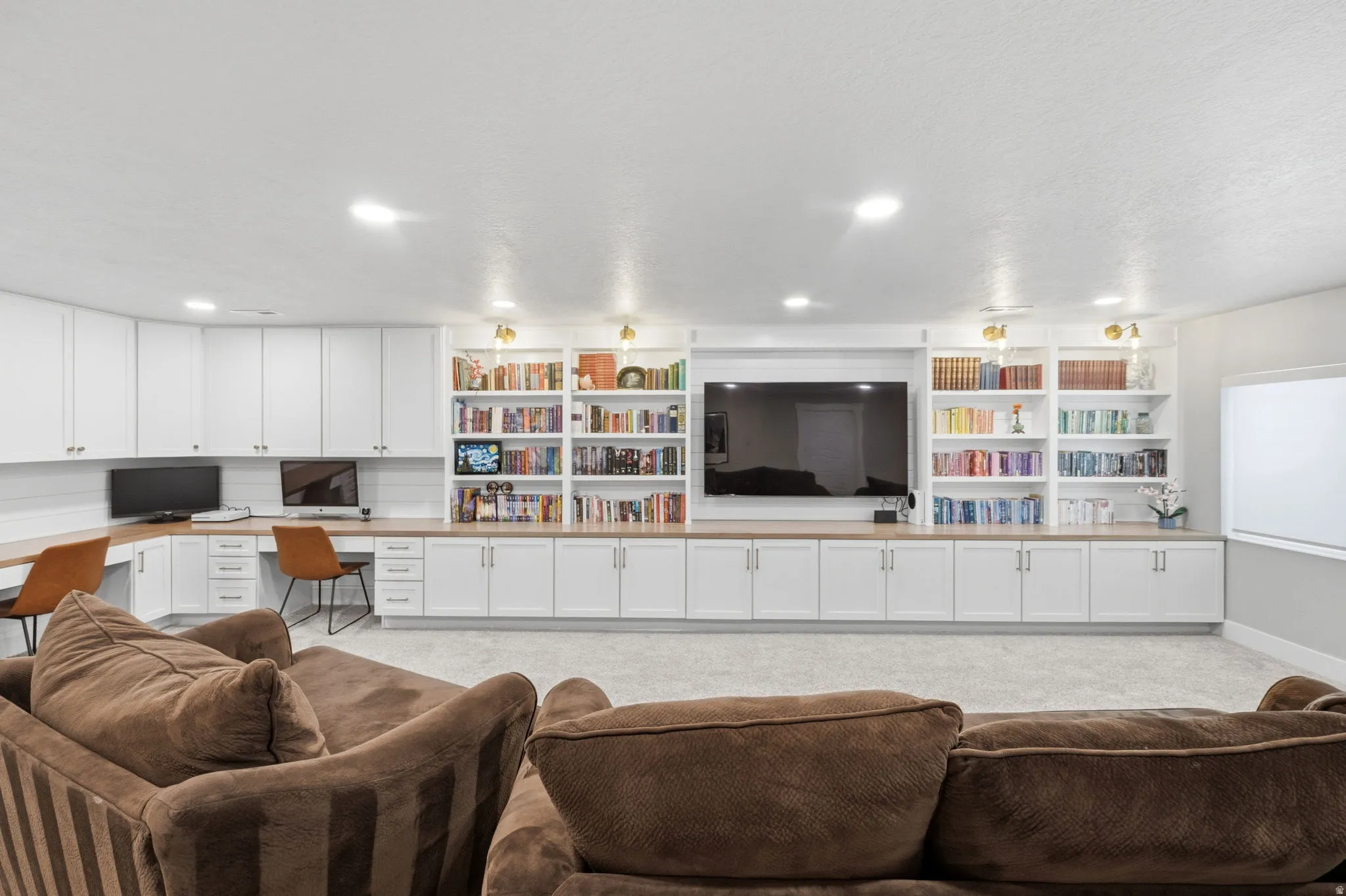 Living room with built in custom cabinetry, desk, light carpet, and recessed lighting