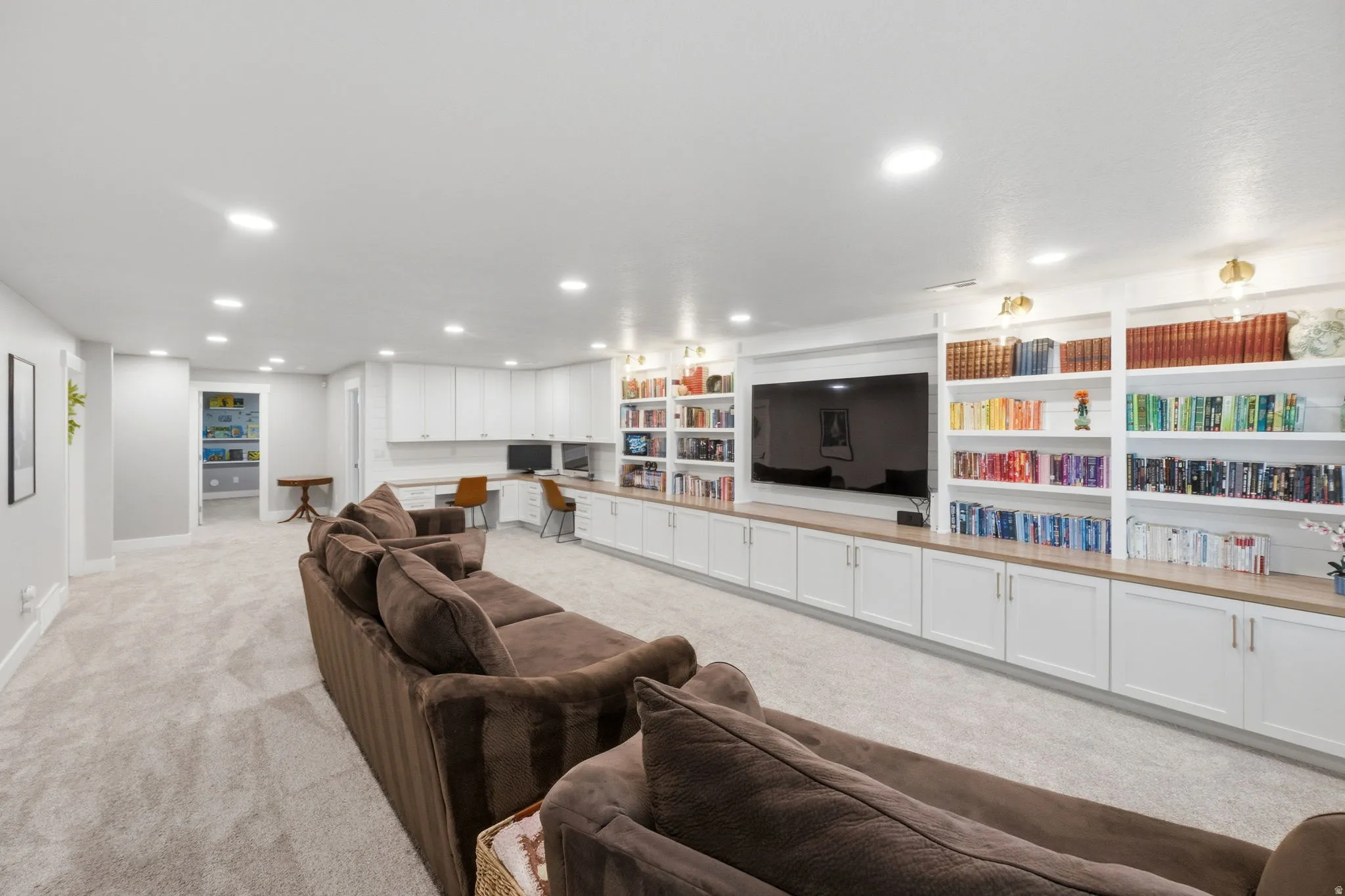 Living room with built in custom cabinetry, desk, light carpet, and recessed lighting