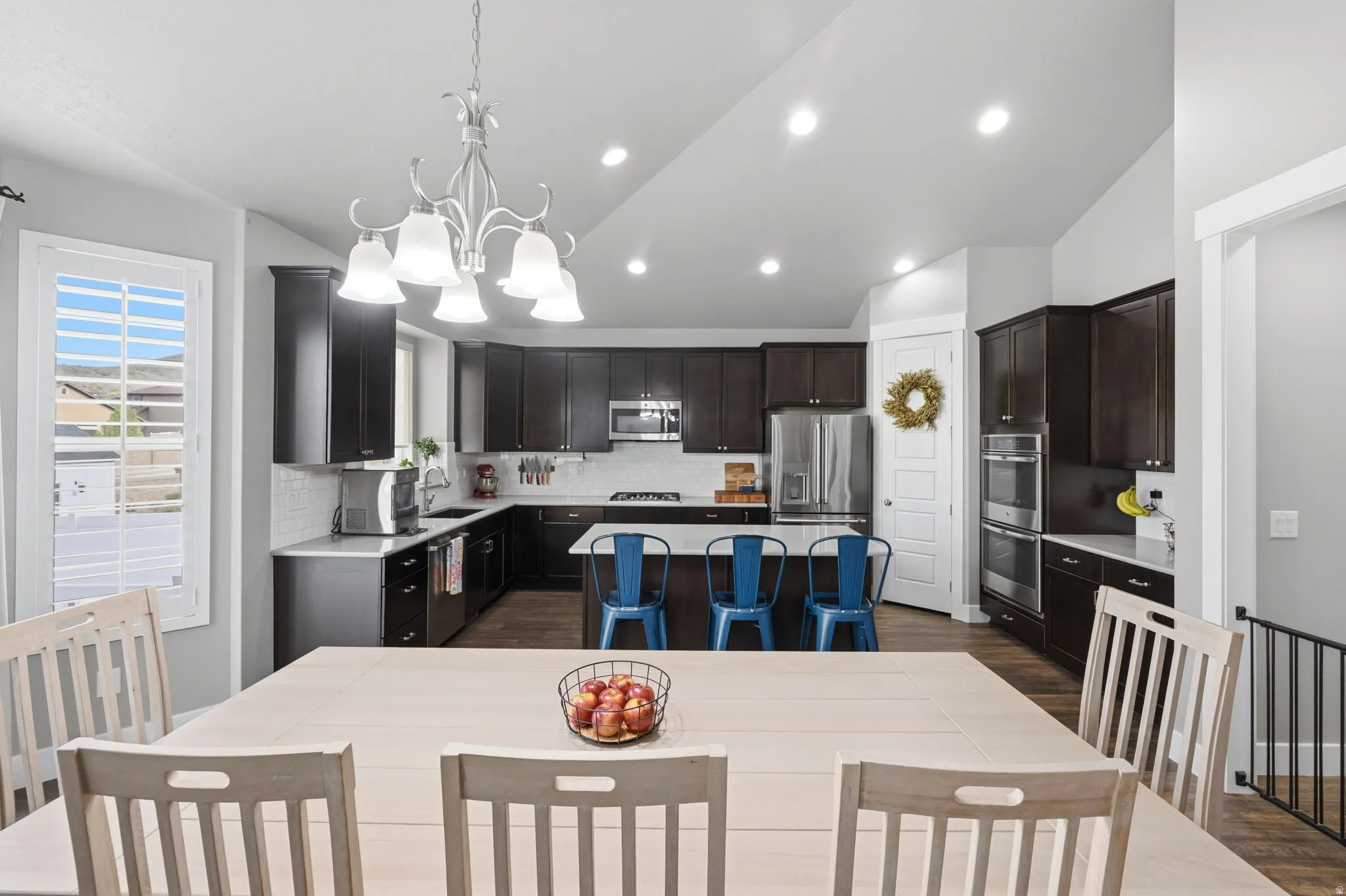 Dining space featuring vaulted ceiling, dark wood-type flooring, and hanging lights