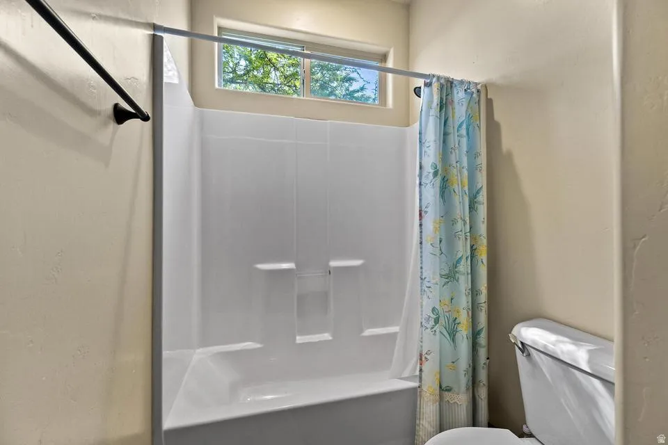 Full bath featuring toilet and shower / bathtub combination with curtain