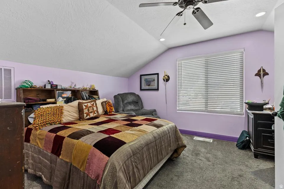 Bedroom featuring a textured ceiling, carpet flooring, and a ceiling fan