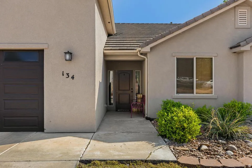 Entrance to property featuring a garage, stucco siding, and a tile roof