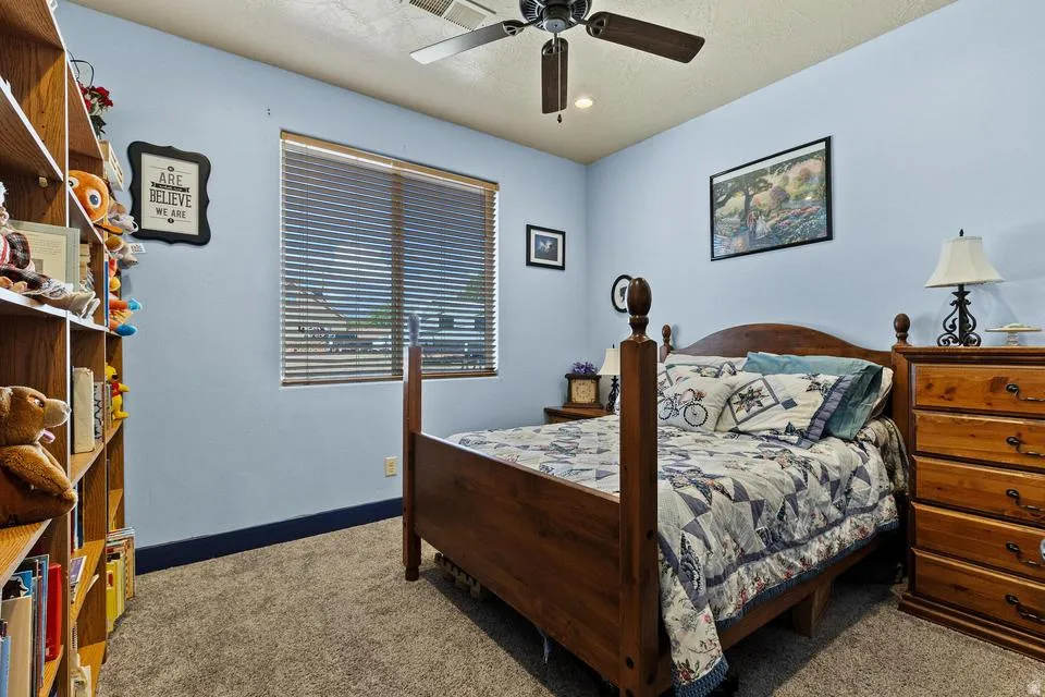 Bedroom with carpet floors, a ceiling fan, and a textured ceiling