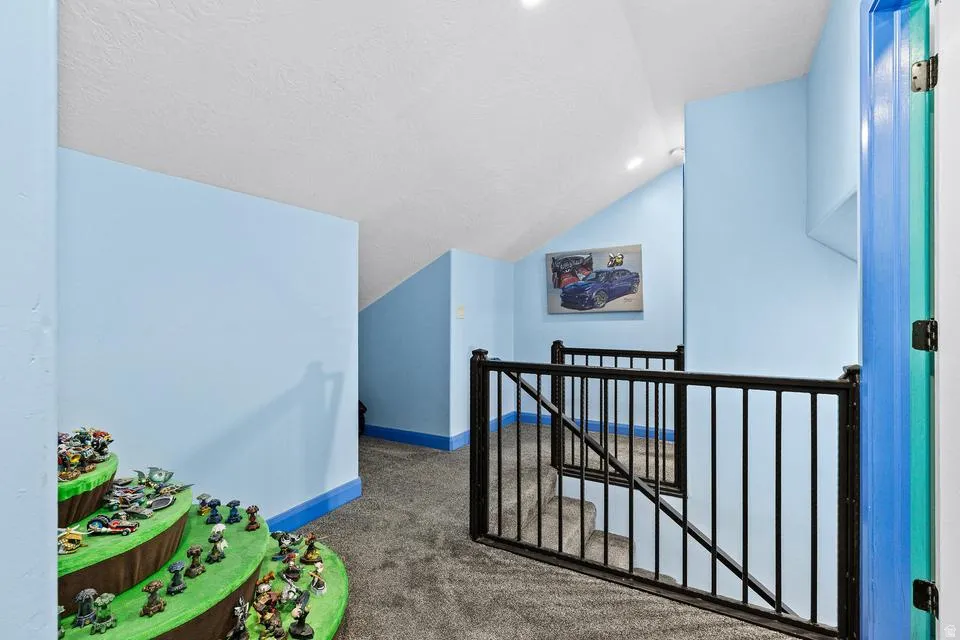 Playroom with vaulted ceiling and dark carpet