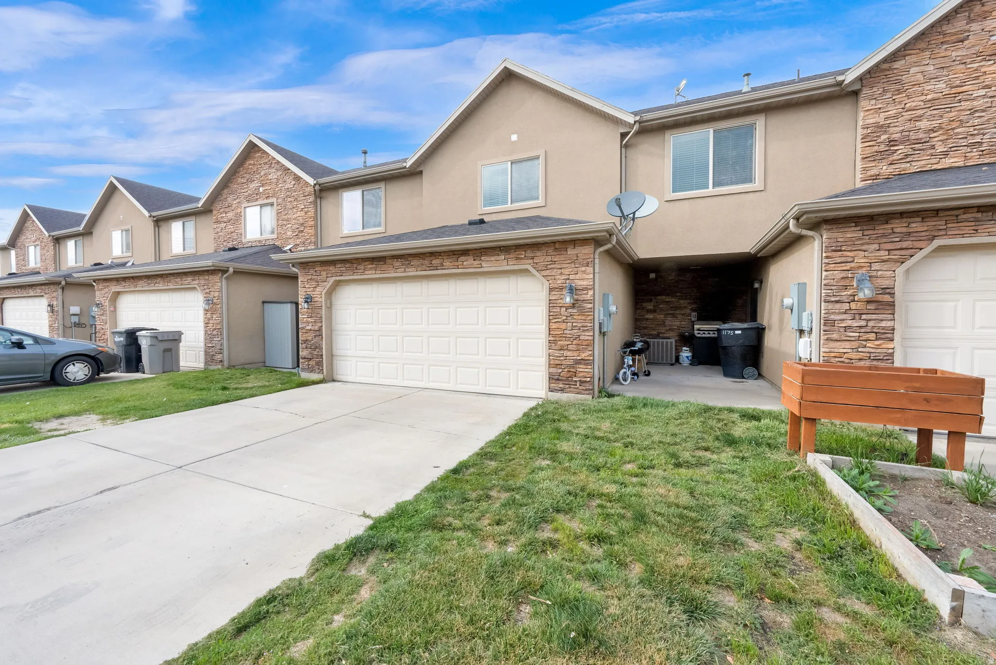 Traditional-style house with stucco siding, a front yard, driveway, and stone siding