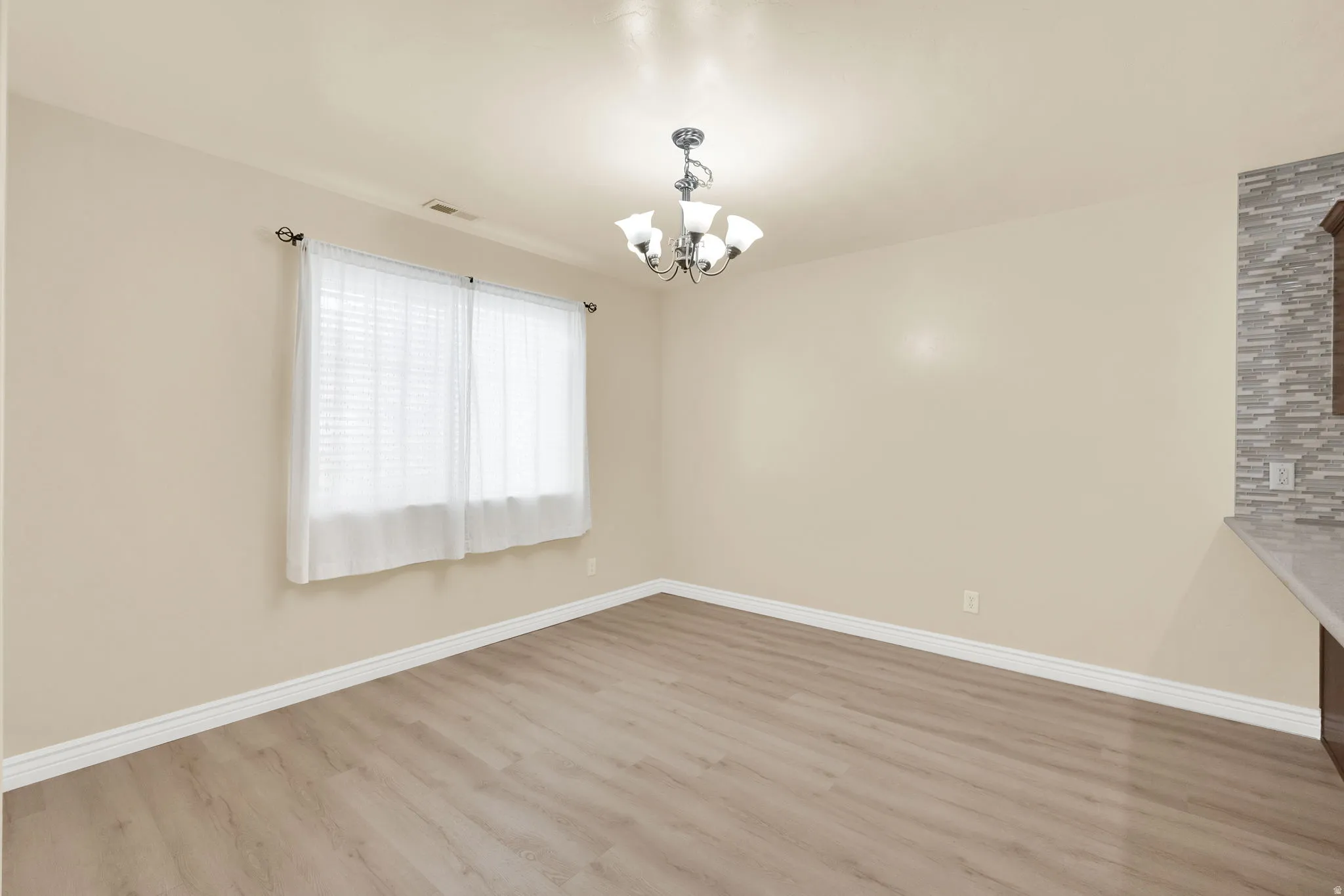 Unfurnished dining area featuring light wood finished floors and hanging lights