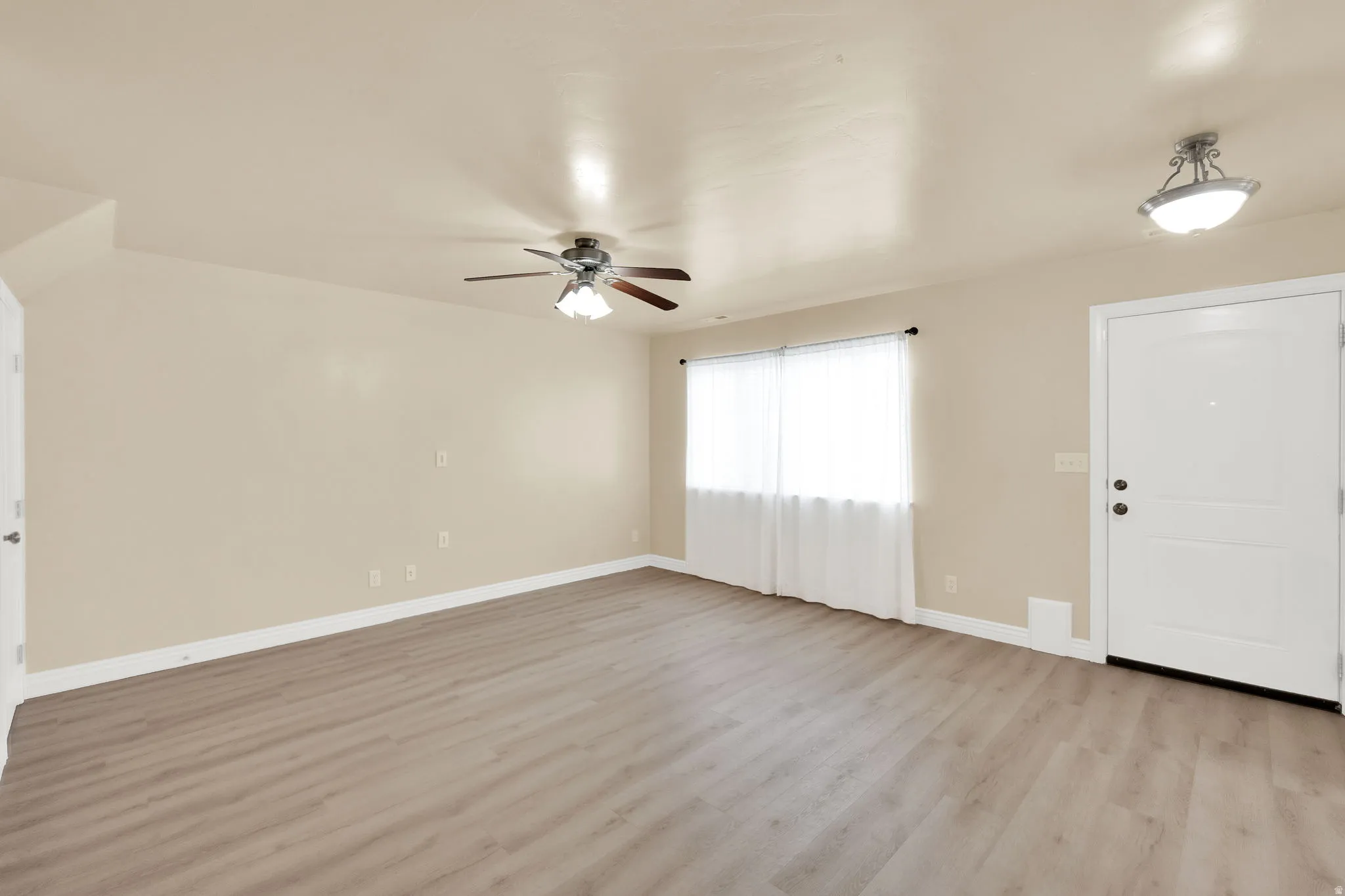 Foyer entrance with light wood finished floors and a ceiling fan