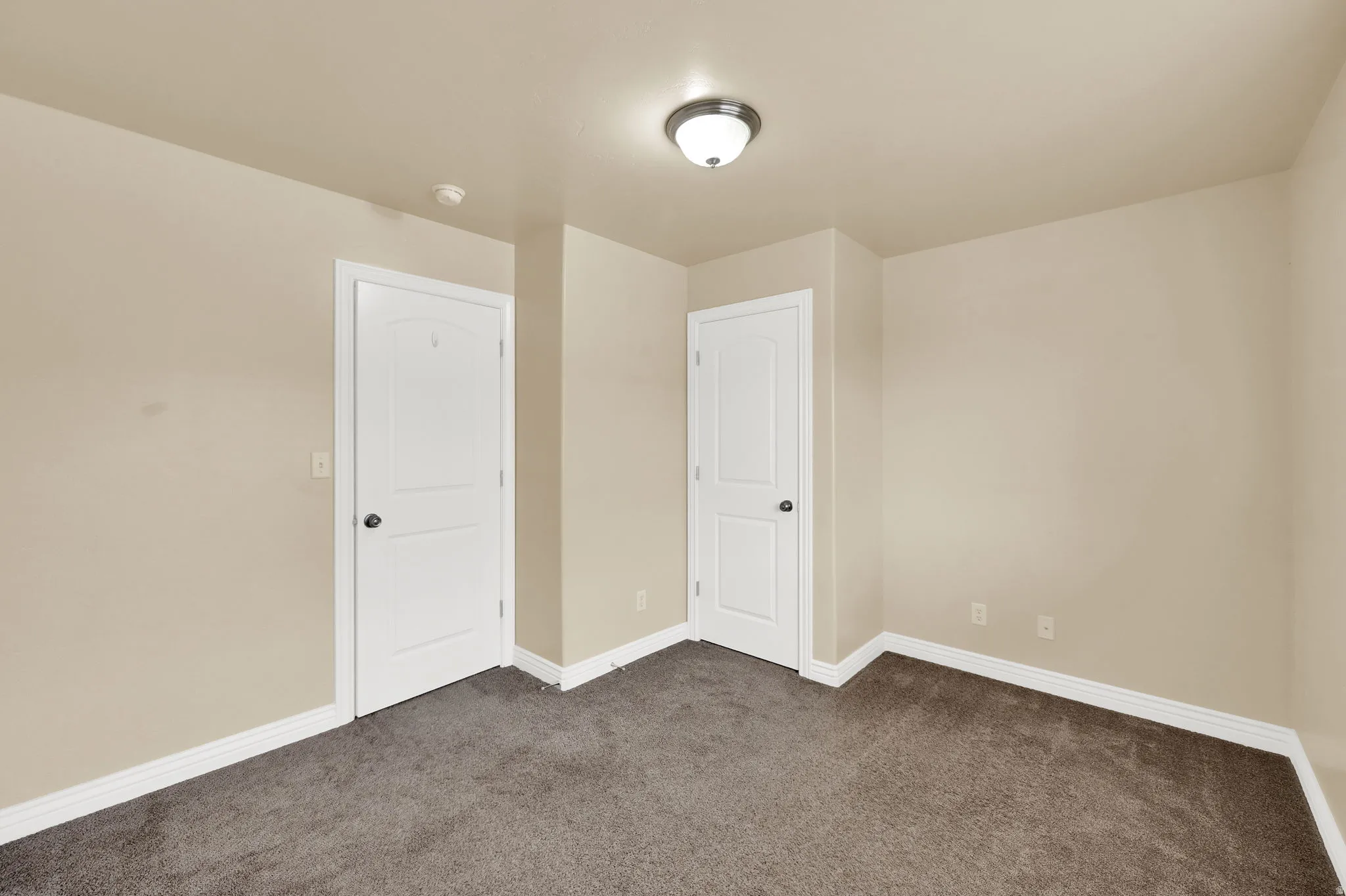 Unfurnished bedroom featuring dark colored carpet and baseboards
