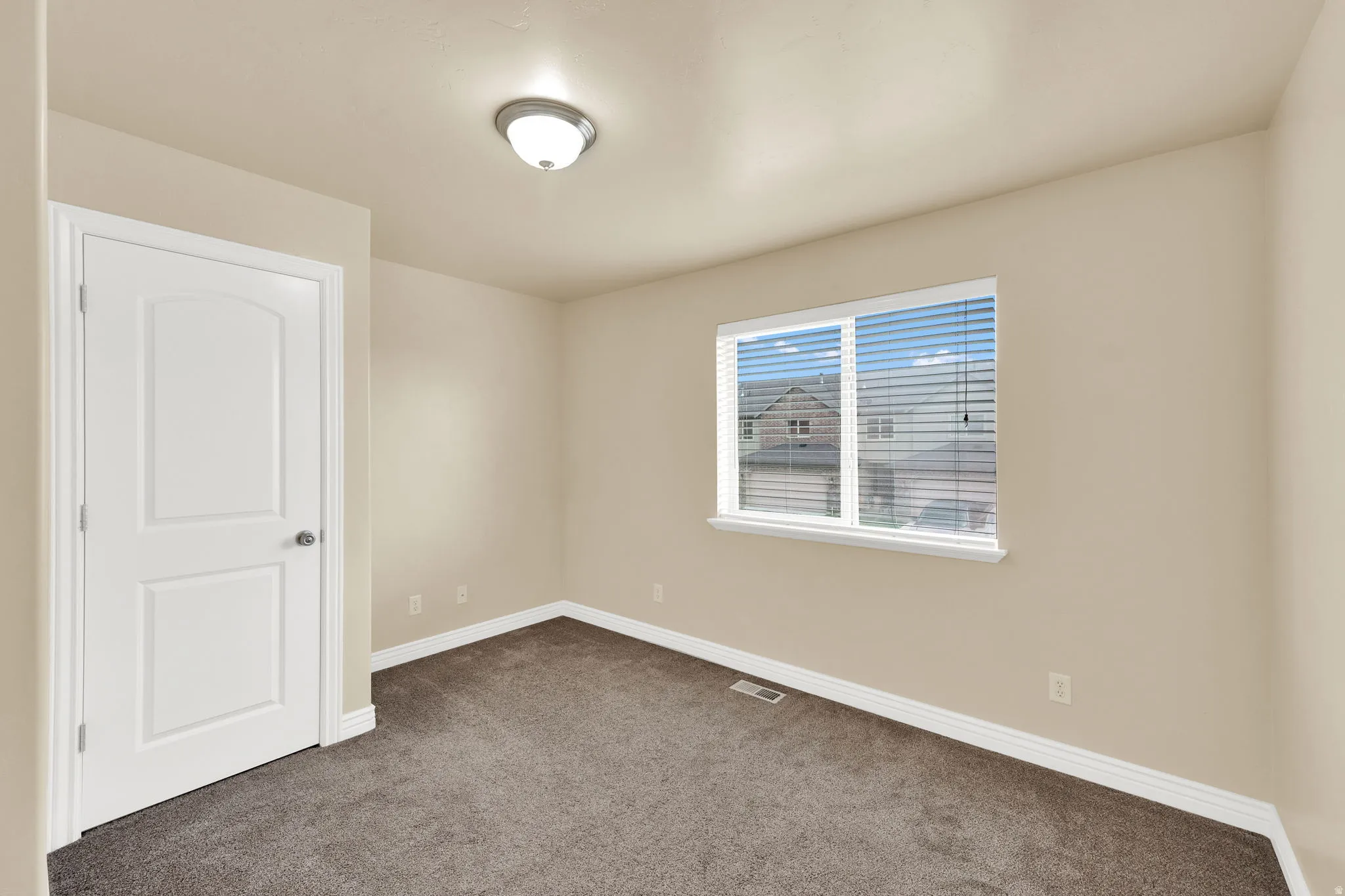 Empty room with dark colored carpet and baseboards