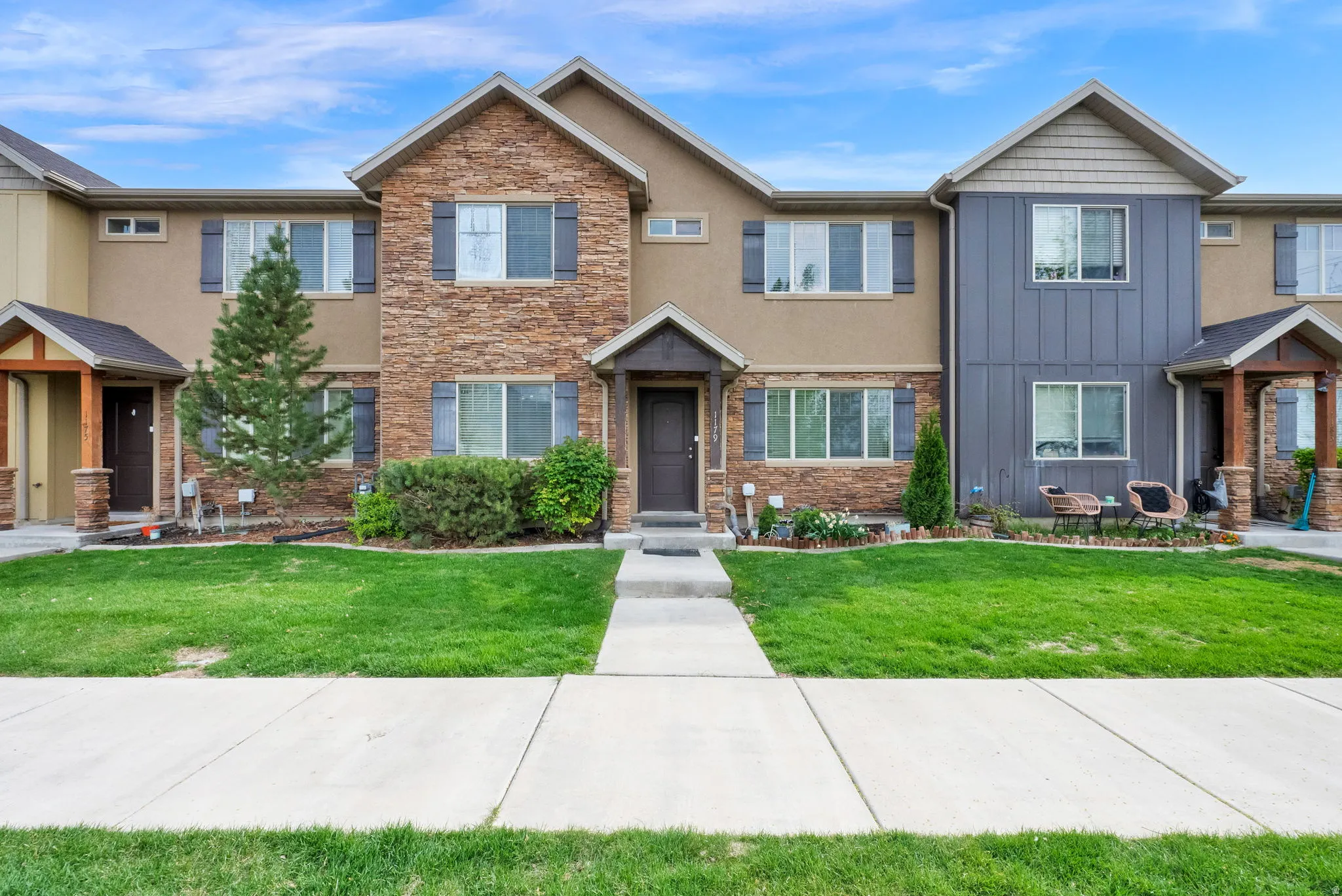 Craftsman inspired home featuring stone siding, a front lawn, board and batten siding, and stucco siding