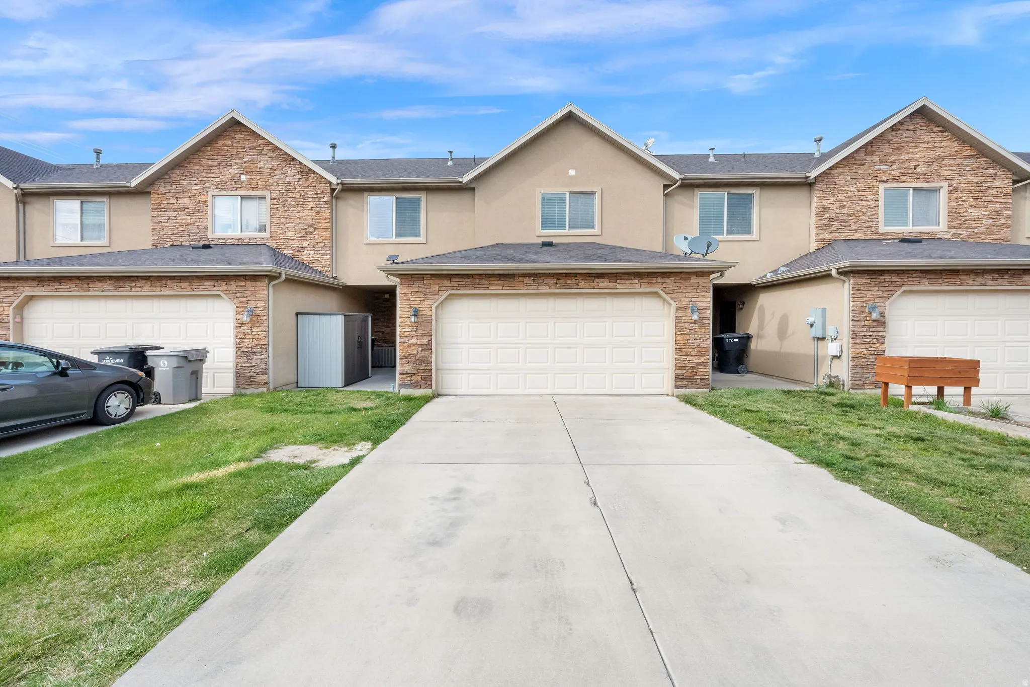 Traditional-style house featuring stone siding, stucco siding, concrete driveway, and a front lawn