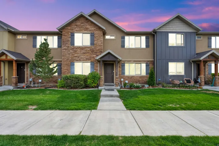 View of front facade with a front lawn, stone siding, board and batten siding, and stucco siding