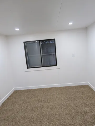 Larger of the two bedrooms, carpeted with recessed lighting