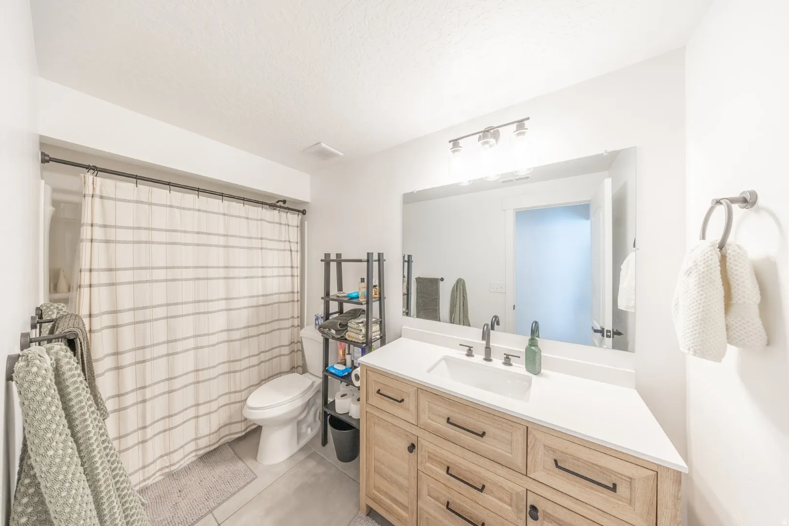 Bathroom featuring vanity, curtained shower, light tile patterned floors, and a textured ceiling